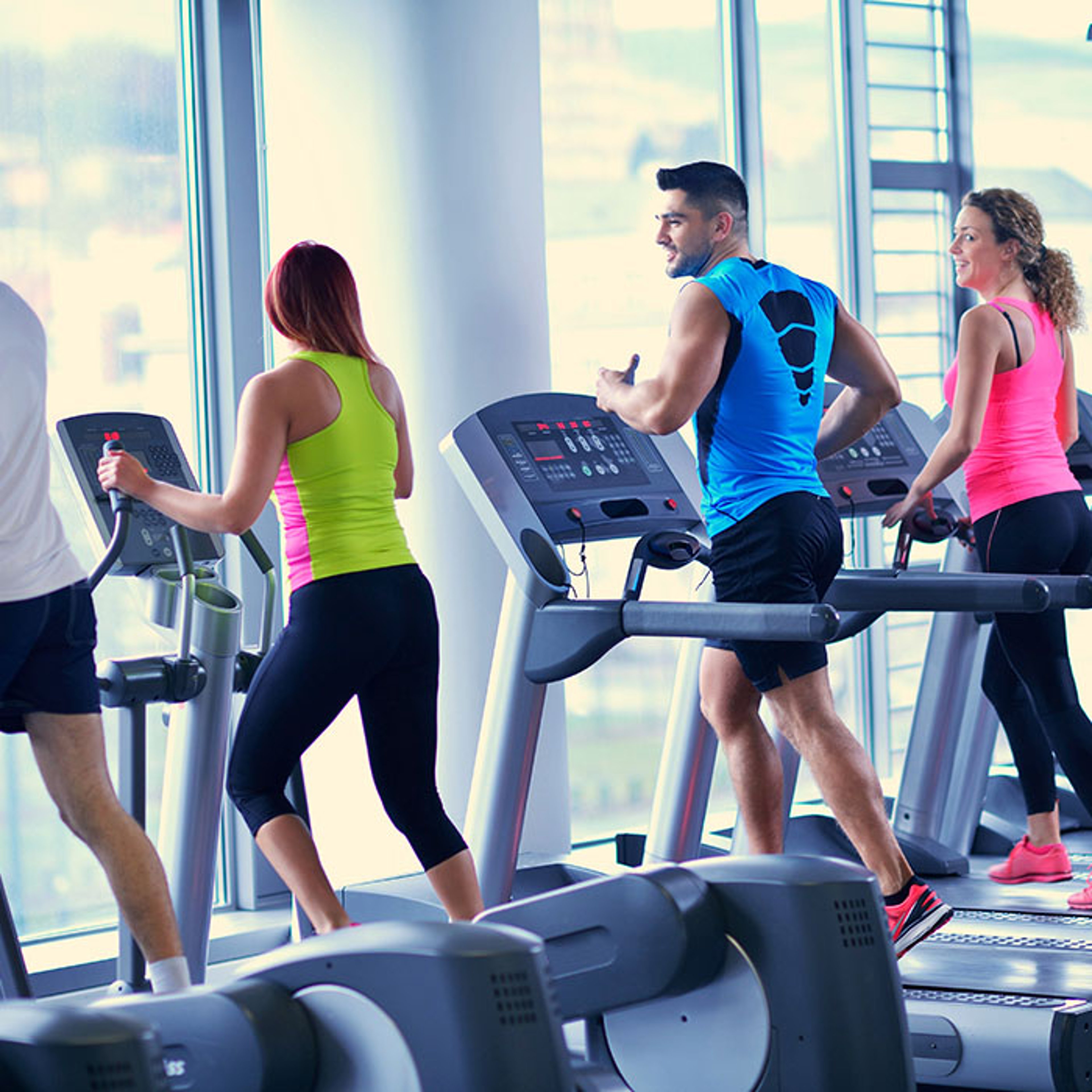 Man and two women exercising on treadmills in luxury gym