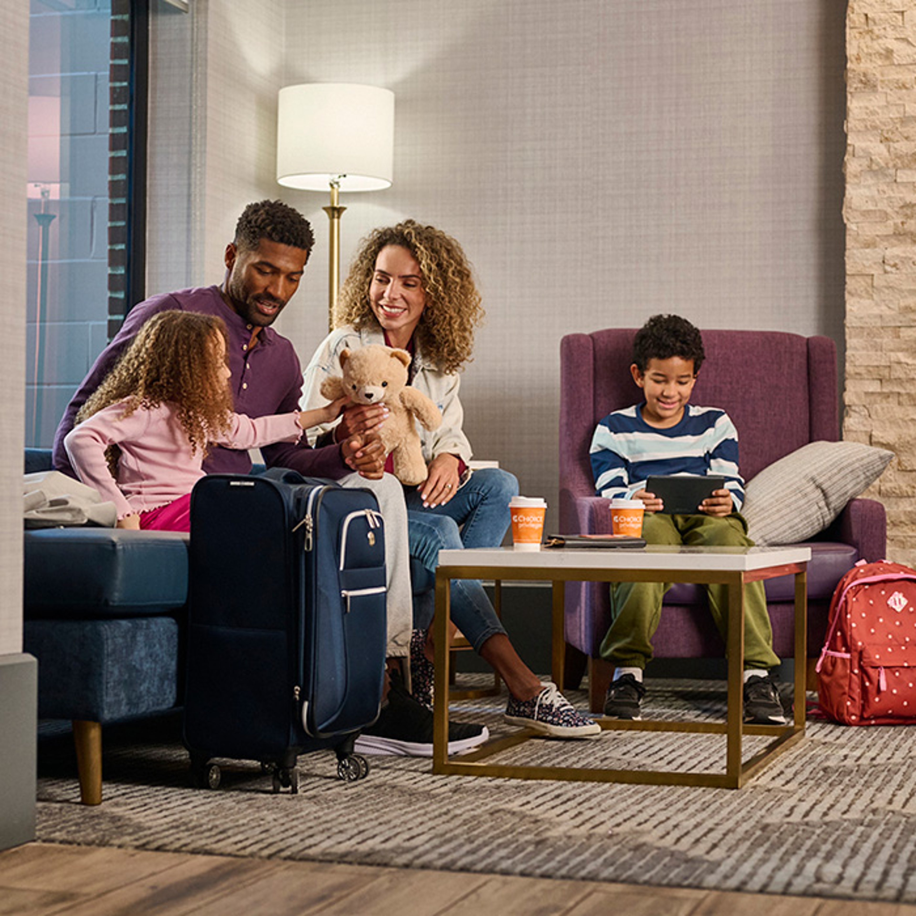Family of four enjoying recreation time in lounge and living room area of hotel