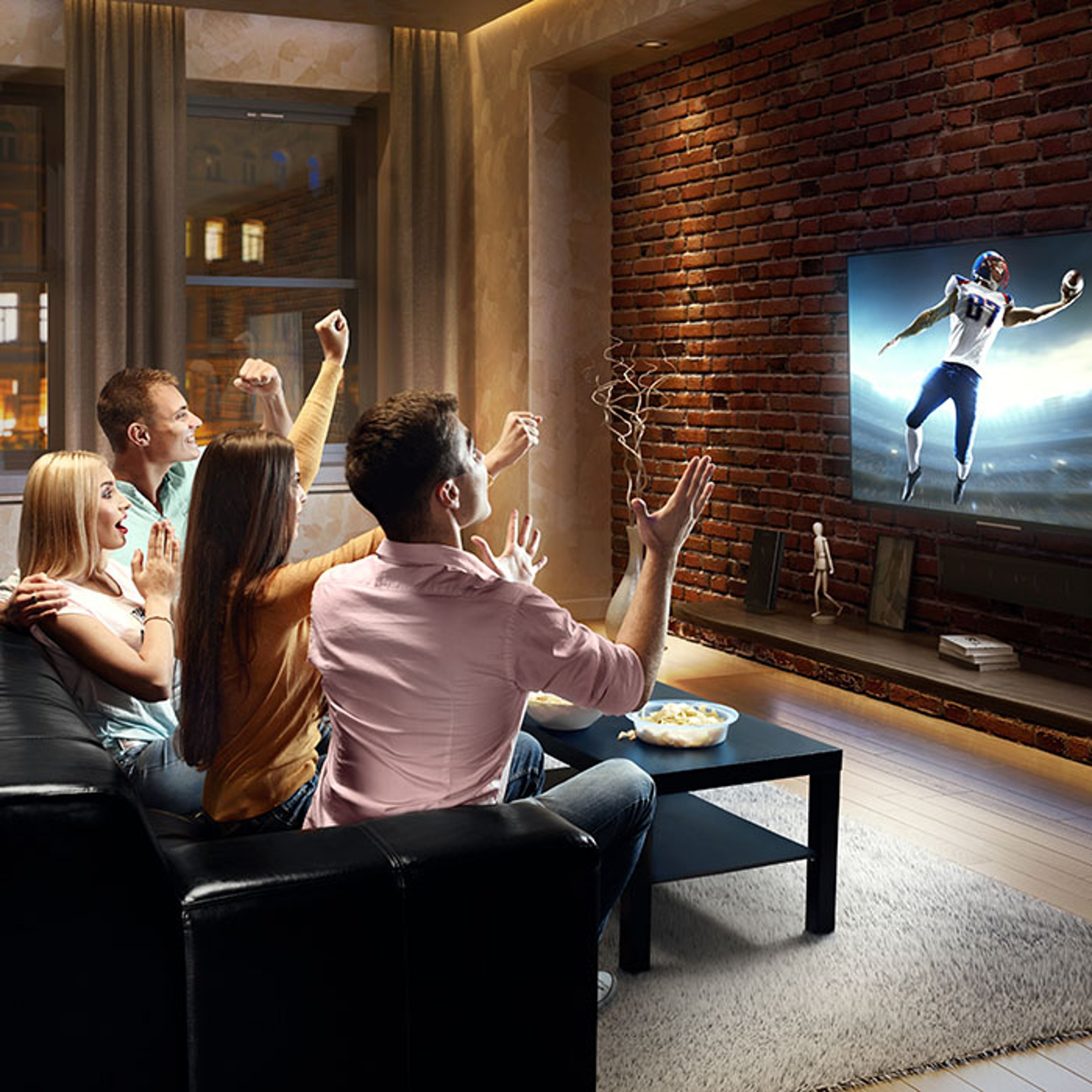 Group of friends watching nighttime football game on big screen TV in entertainment room