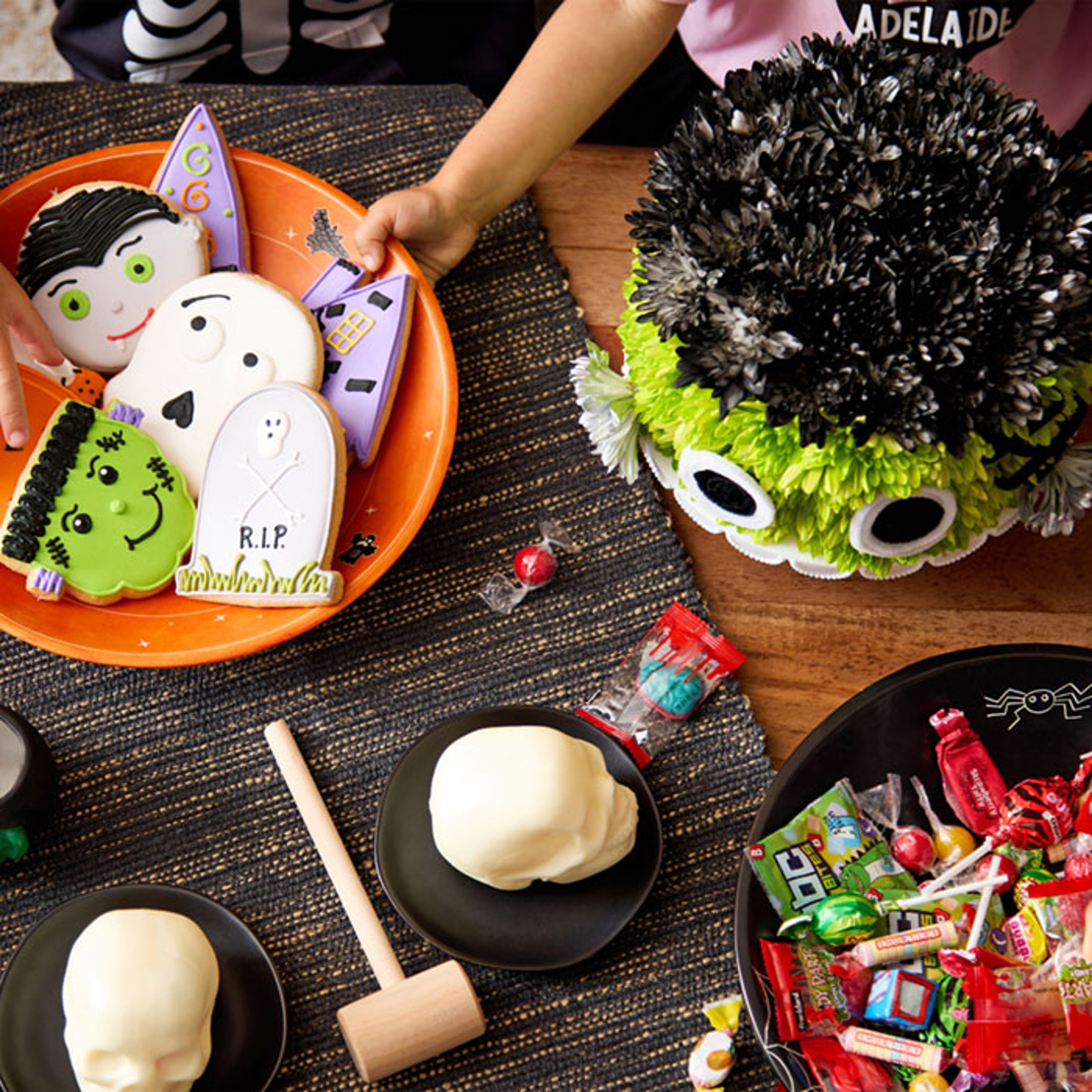 Child's hand reaching for assorted Halloween treats on table