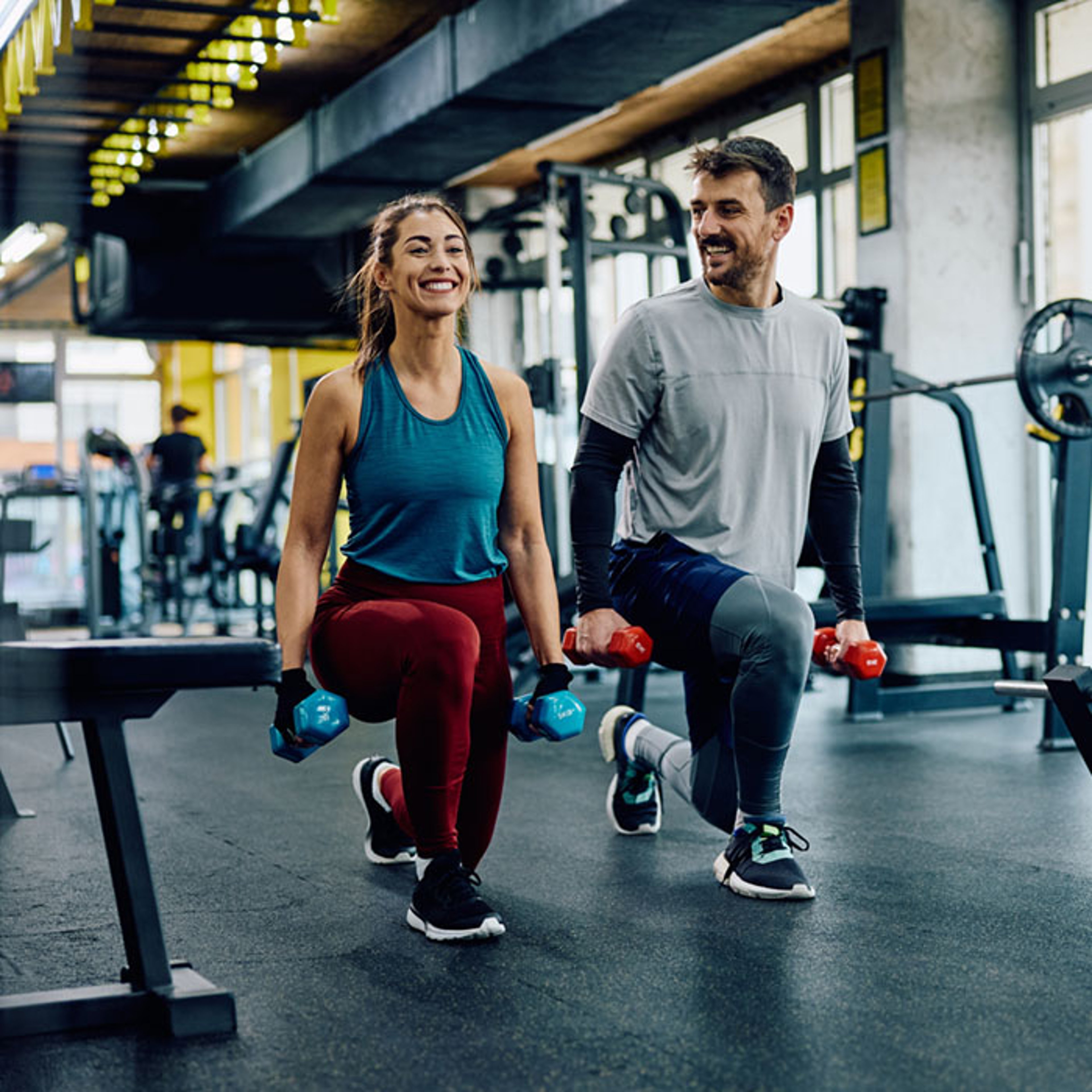 Man and woman doing weight training lunges in luxury gym