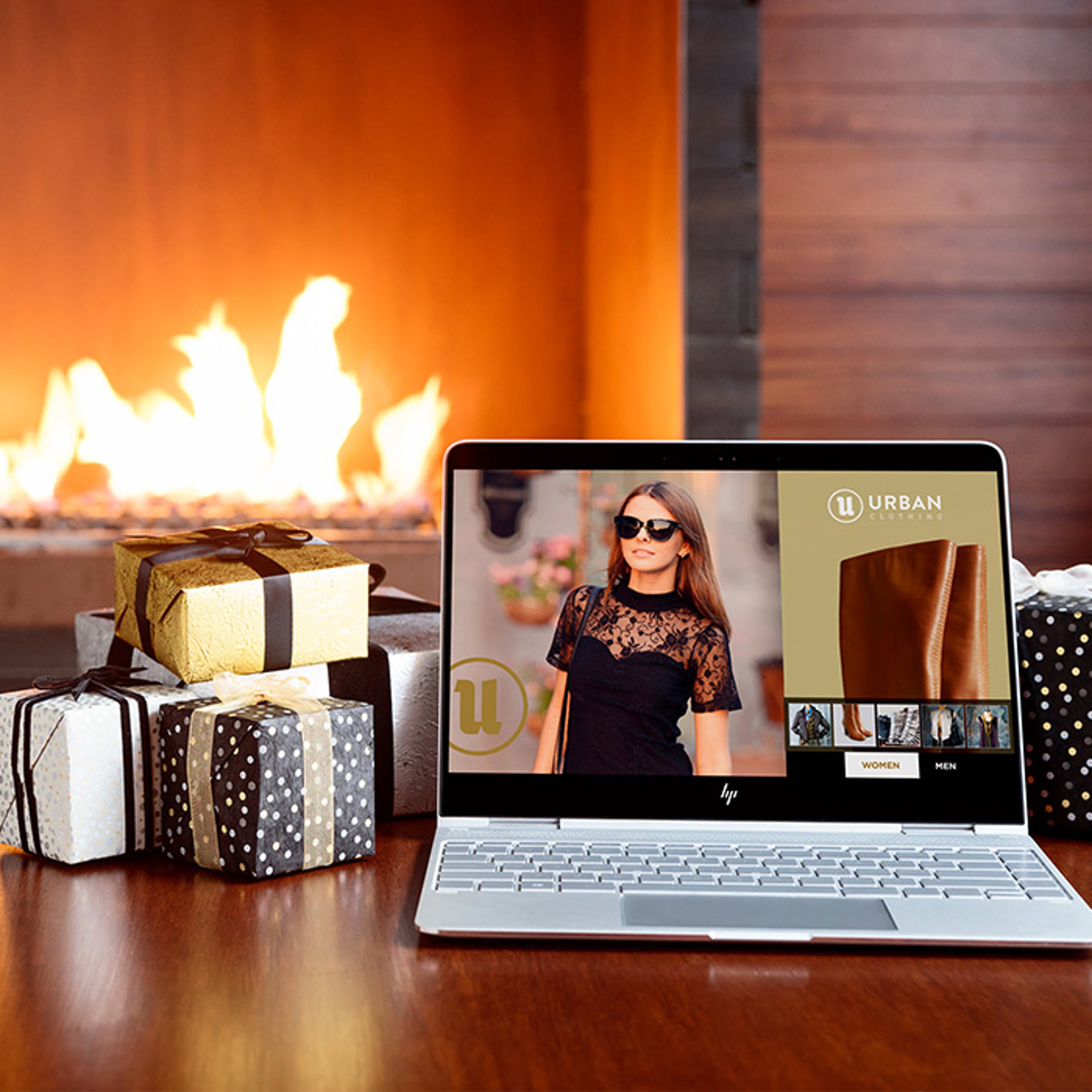 View of fireplace with holiday gifts on table with open HP laptop showing Urban Clothing ad