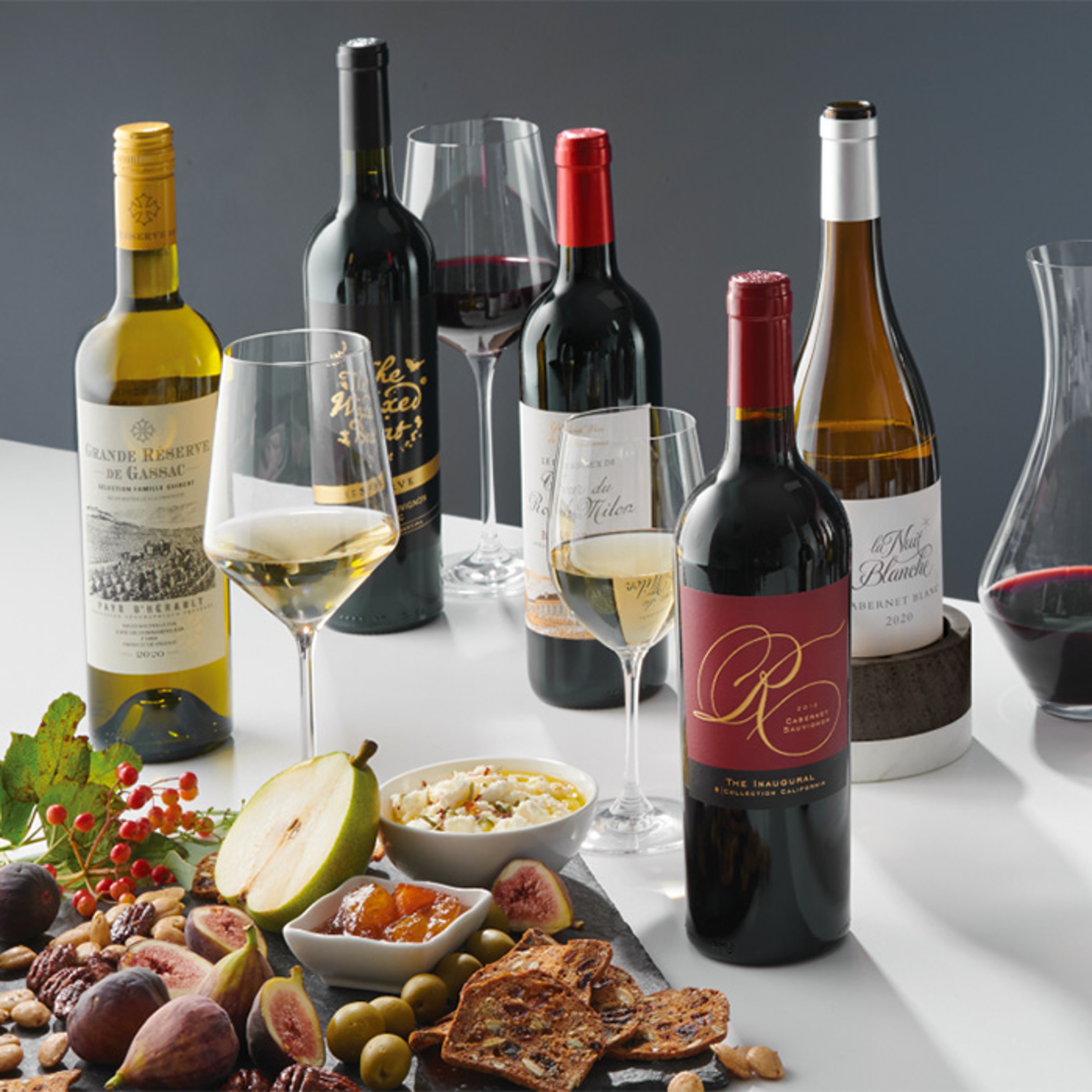 Array of wine bottles and decanter with assorted fruit and charcuterie plate