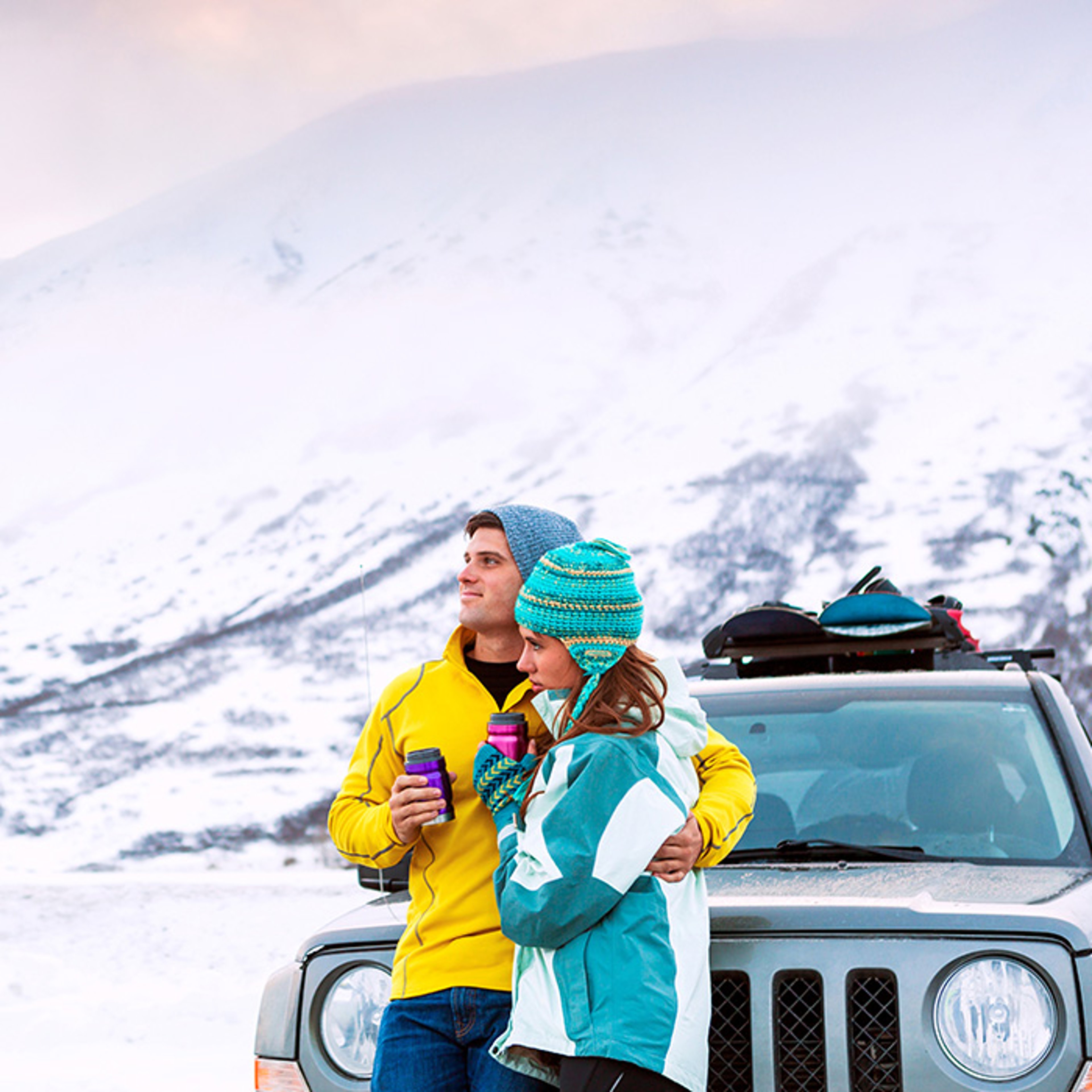 Couple in front of Jeep with snow covered mountain in background