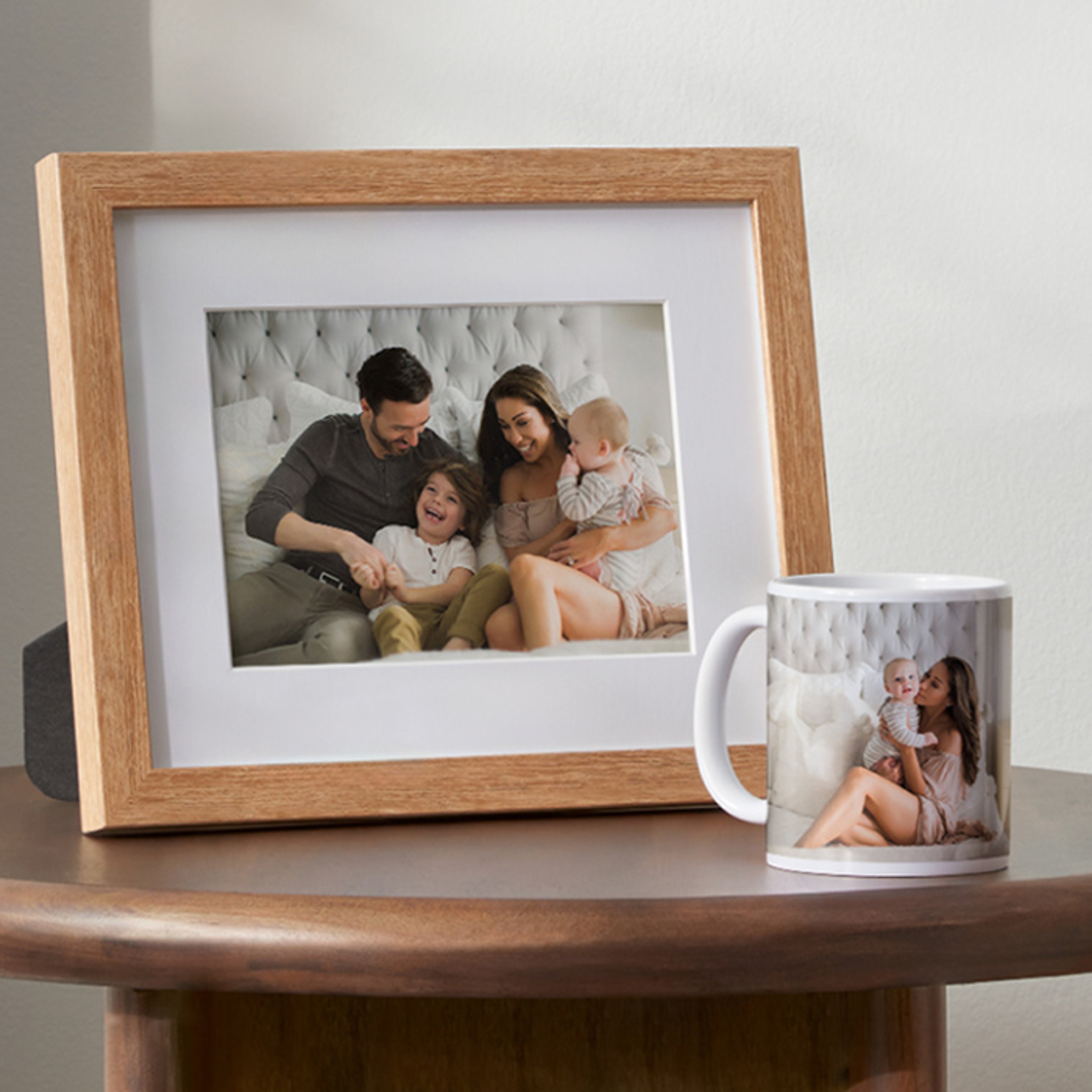 Wooden-framed family photograph and mug with a family image on a wooden surface.