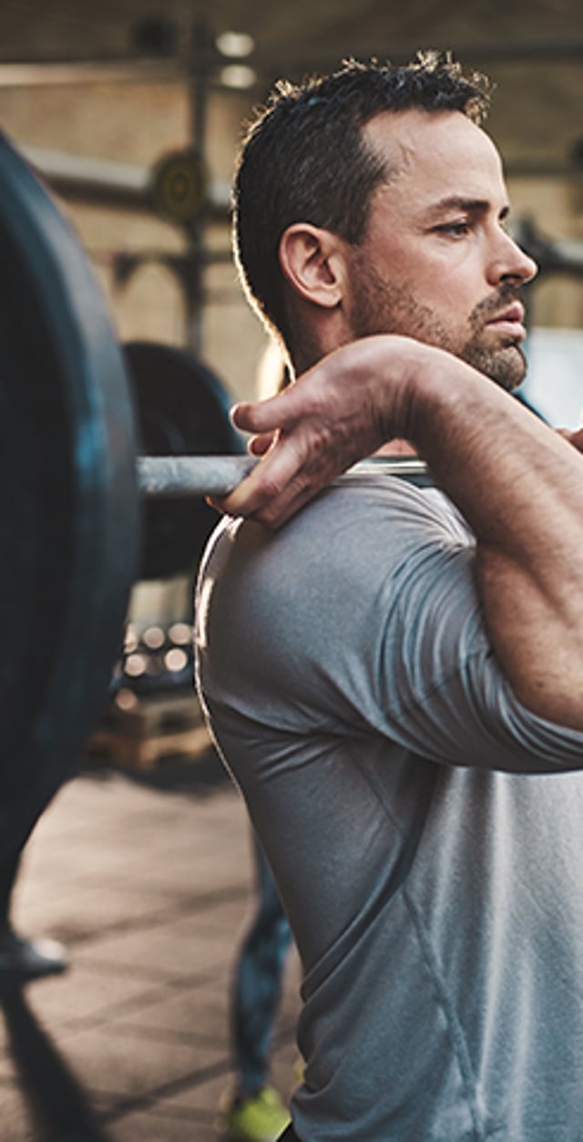 Man lifting a barbell in a gym during a strength-training workout.