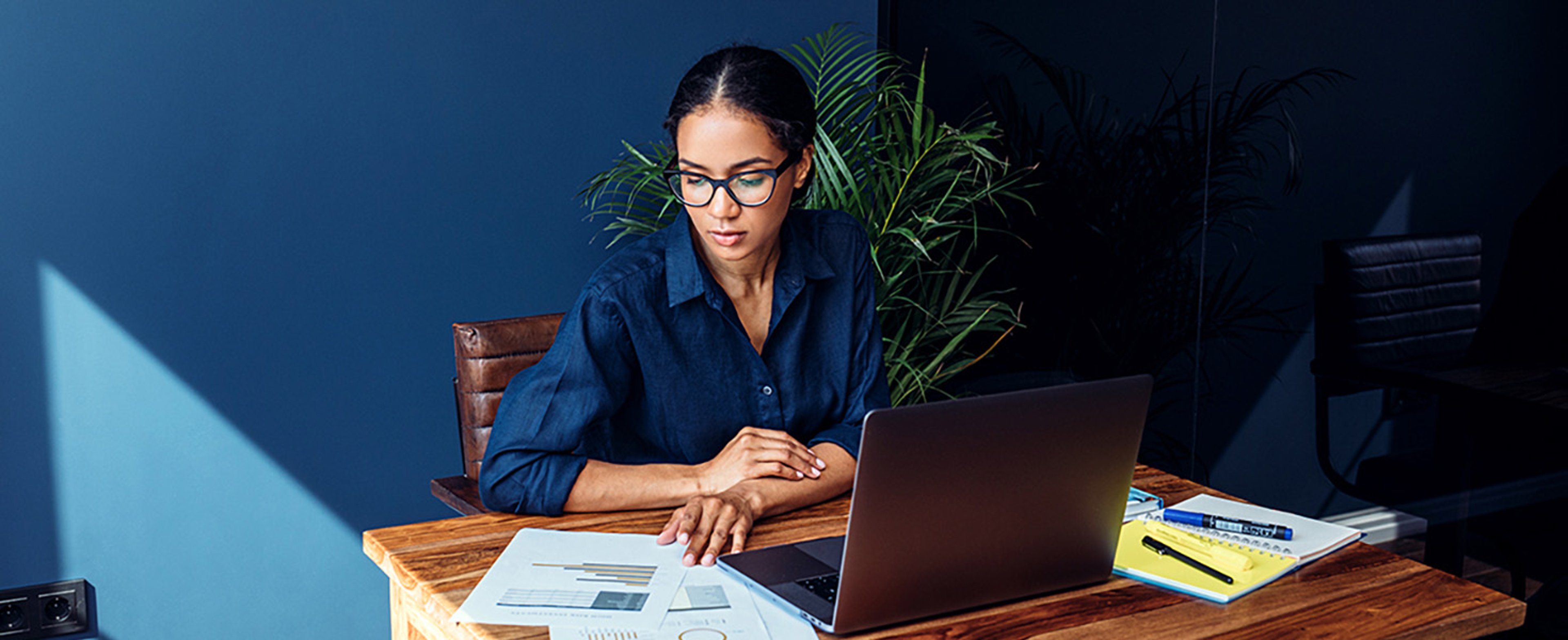 Businesswoman reviewing documents at her desk with laptop