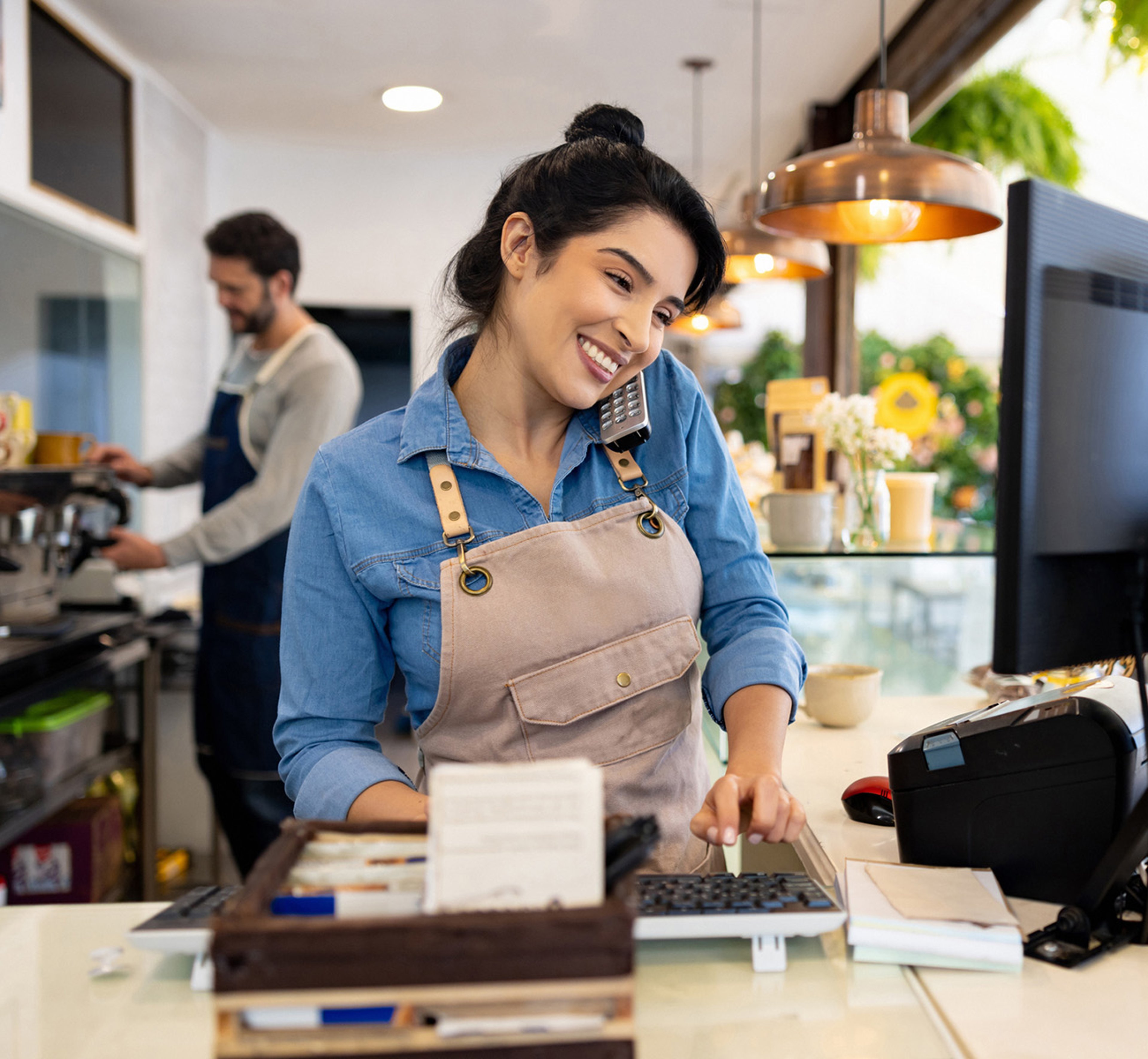 Smiling young woman business owner entering order on computer