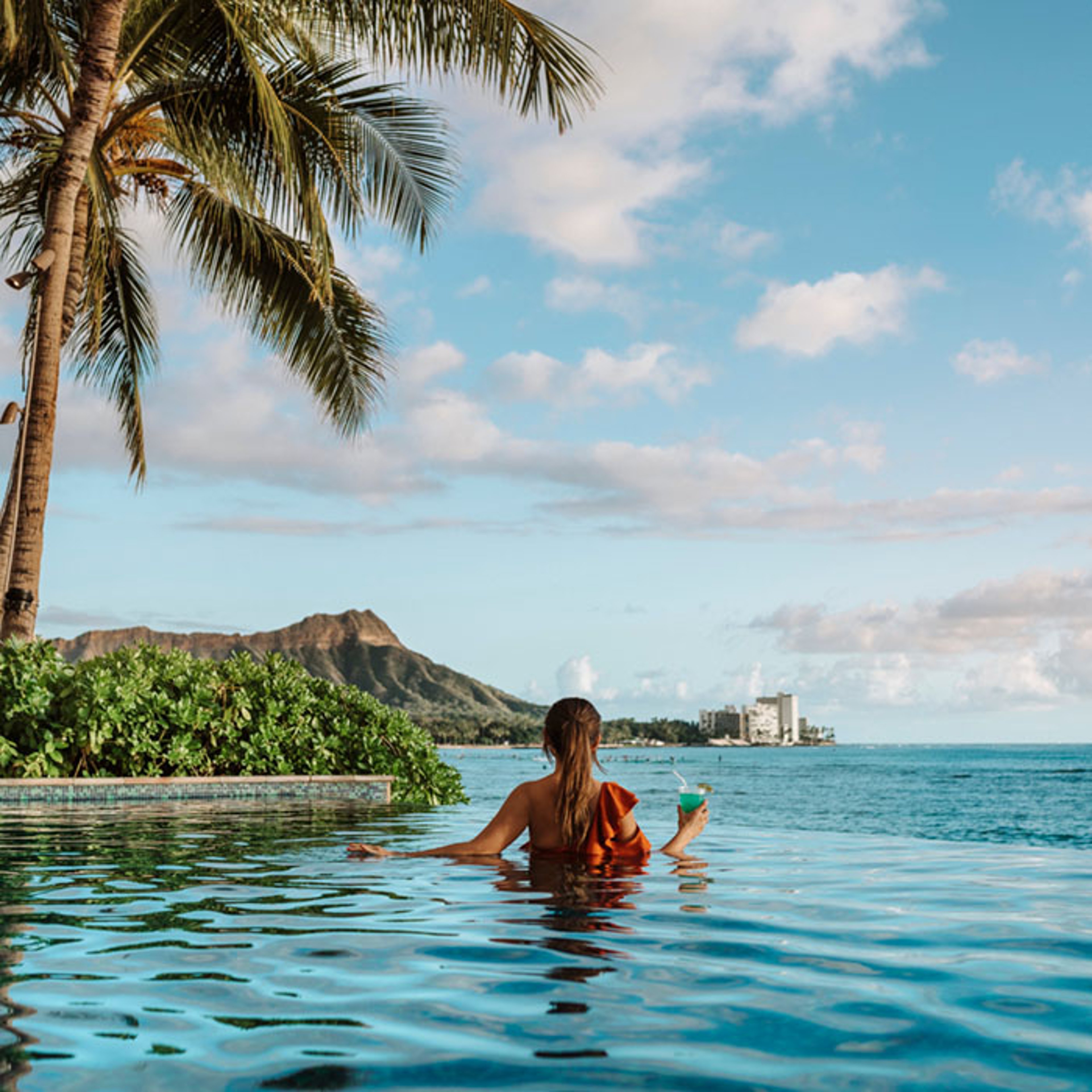 Woman relaxing at tropical island resort in an infinity pool