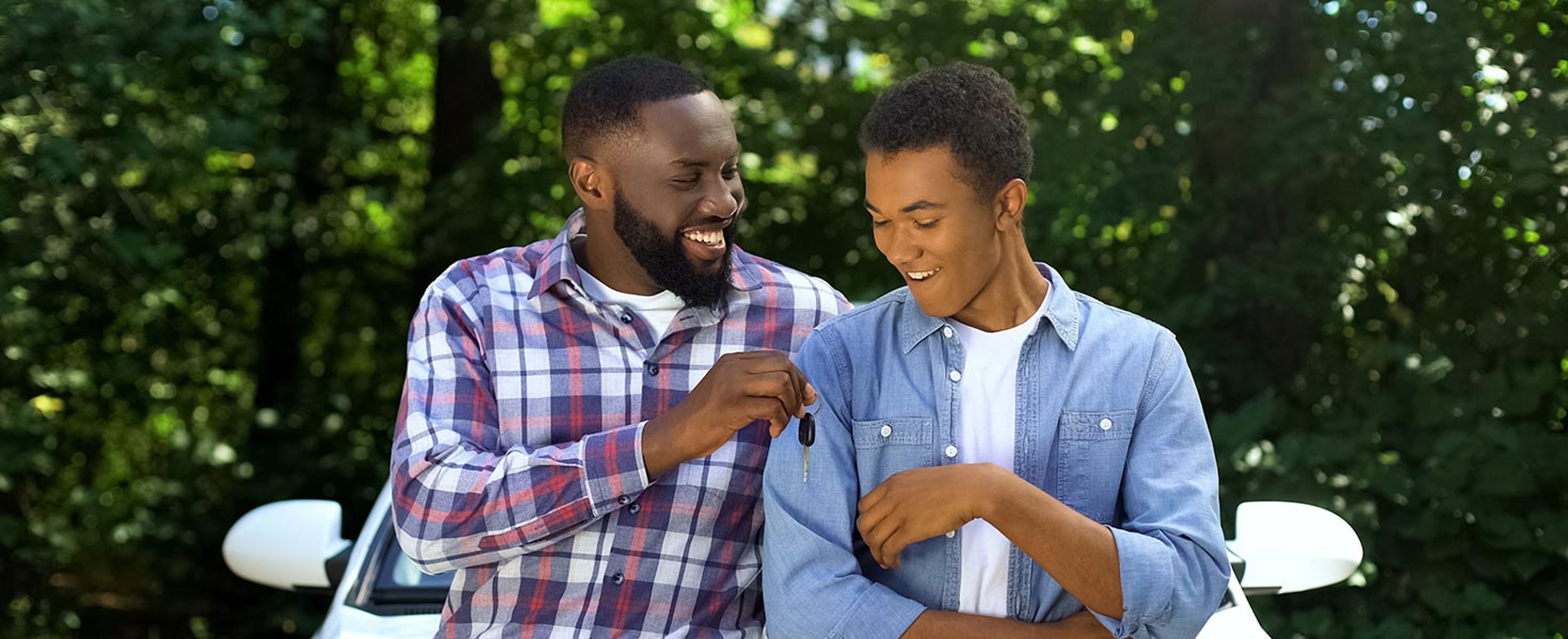 Father handing his teenage son driver car keys