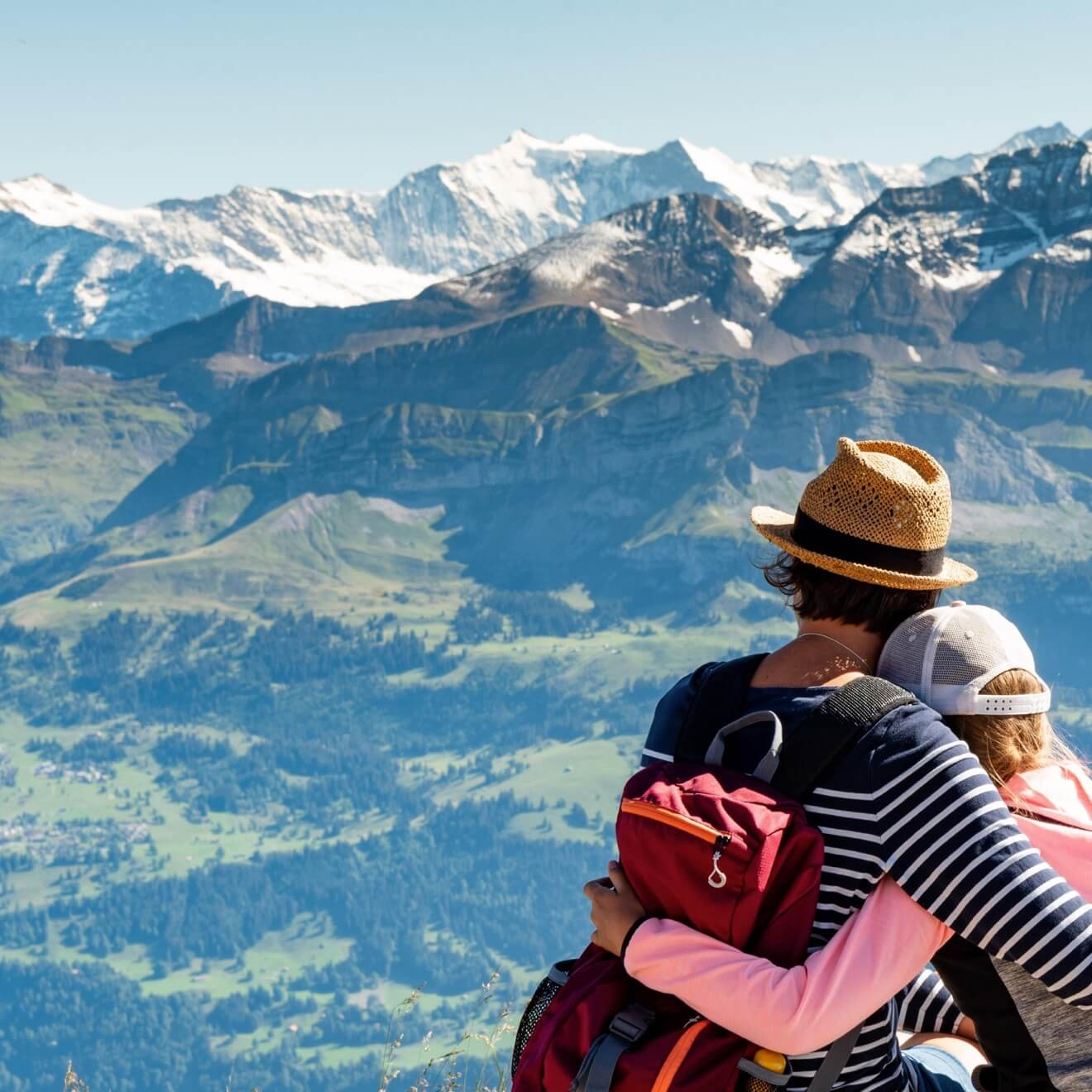 Couple embracing while looking over snowcapped mountain range while on vacation