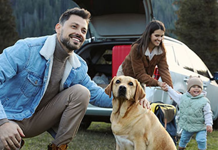 Happy man with dog, mother and her daughter near car in mountains.