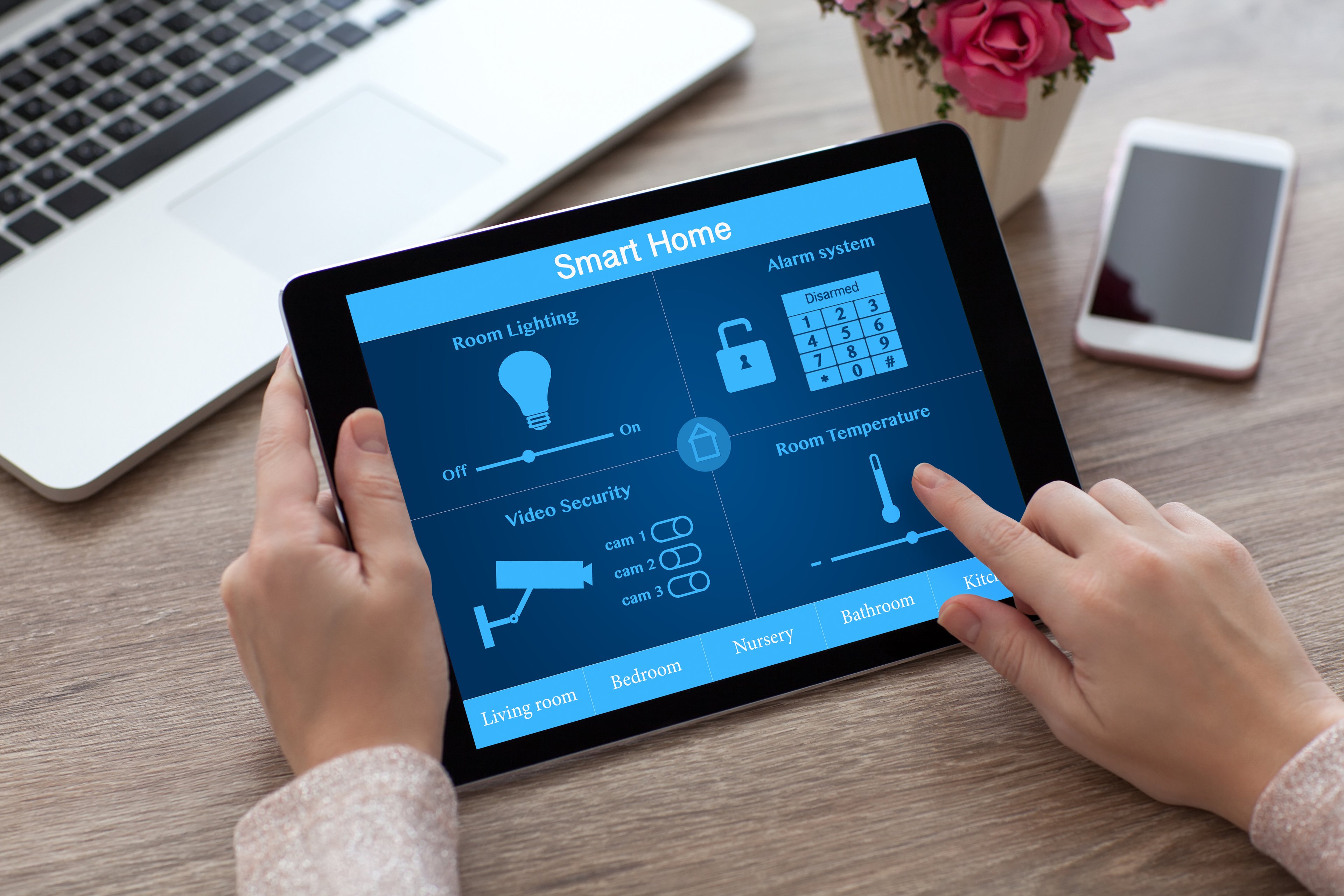 Hands holding tablet with home security app on screen