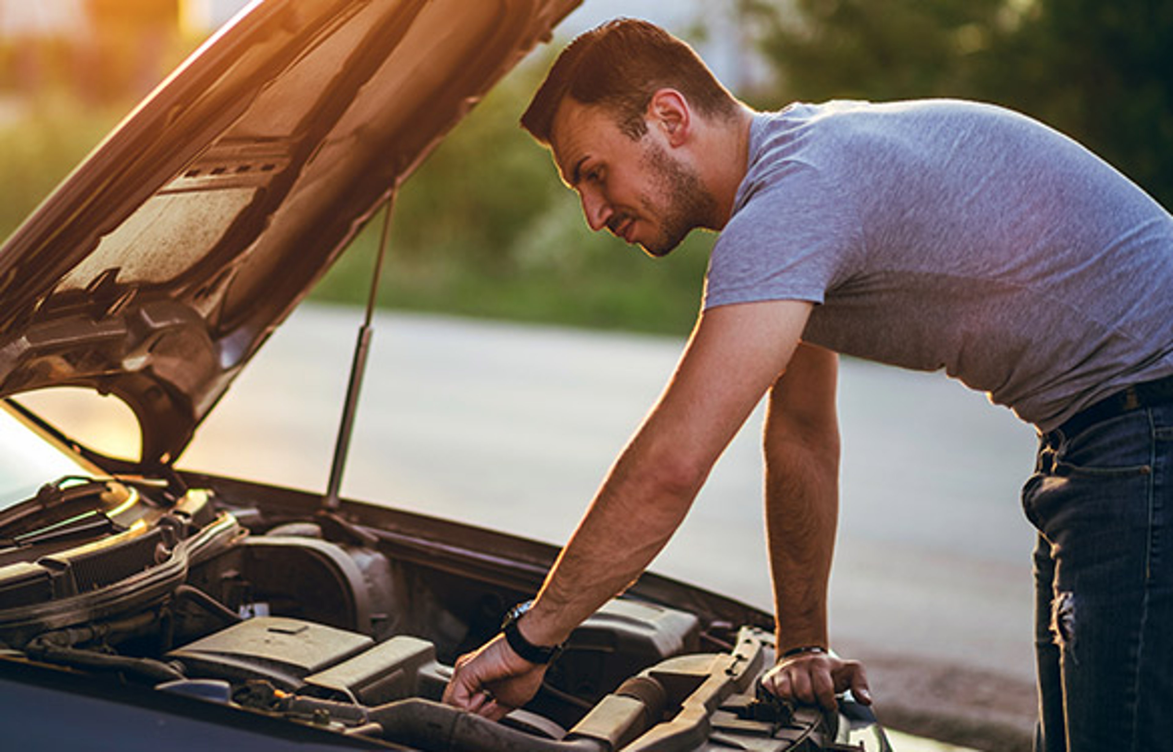 Man looking at the engine of a car looking for a weird smell