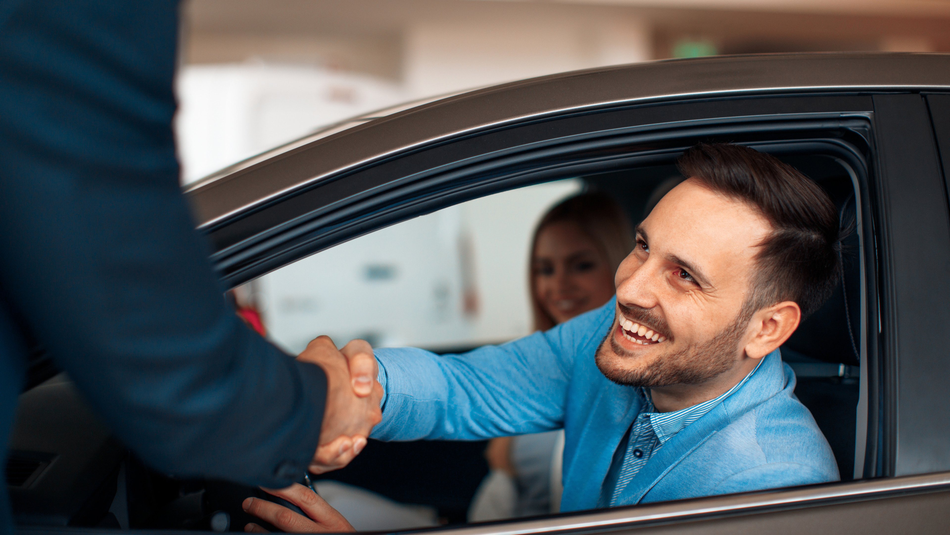 Happy man shaking his car salesman's hand