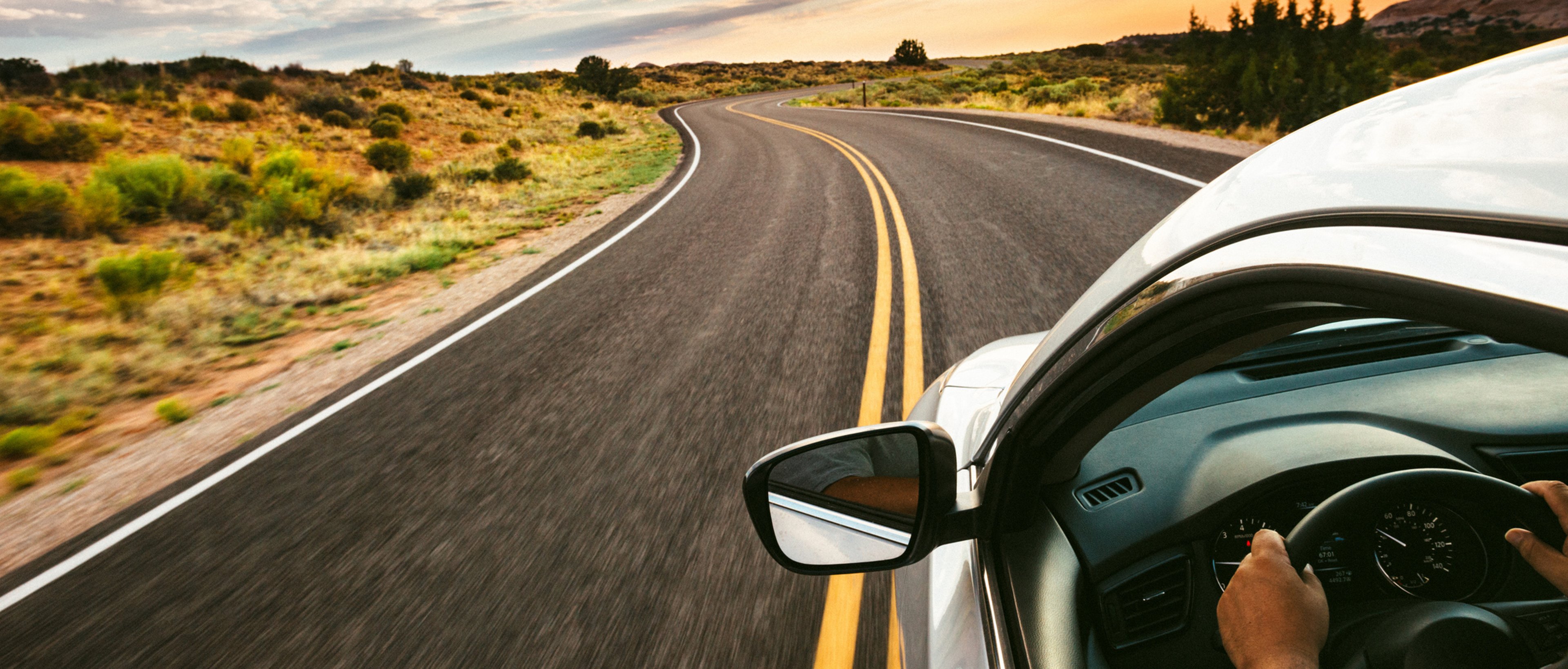Car driving on empty road at dusk