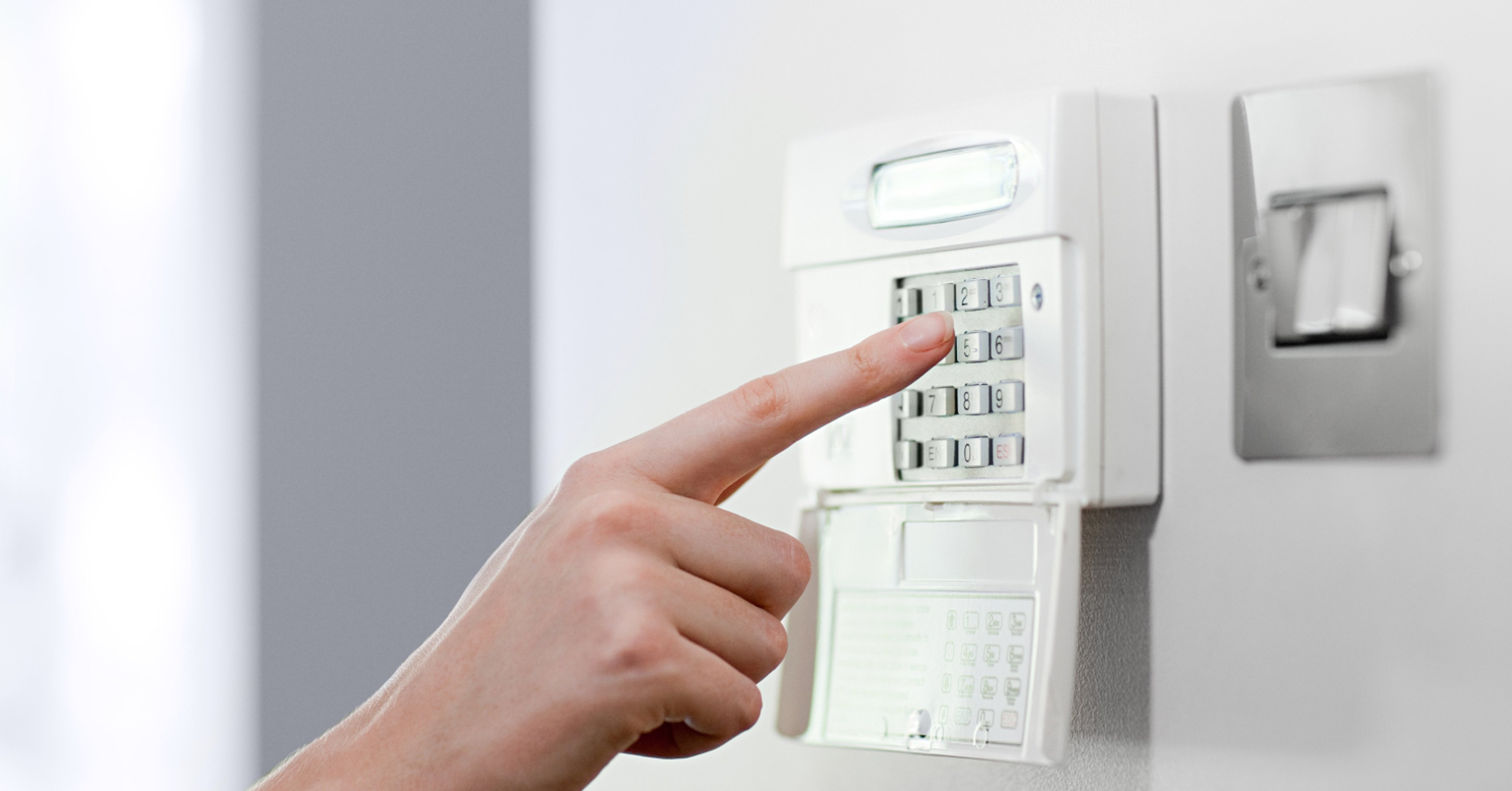 Close up of hand pushing number on keypad of home security system