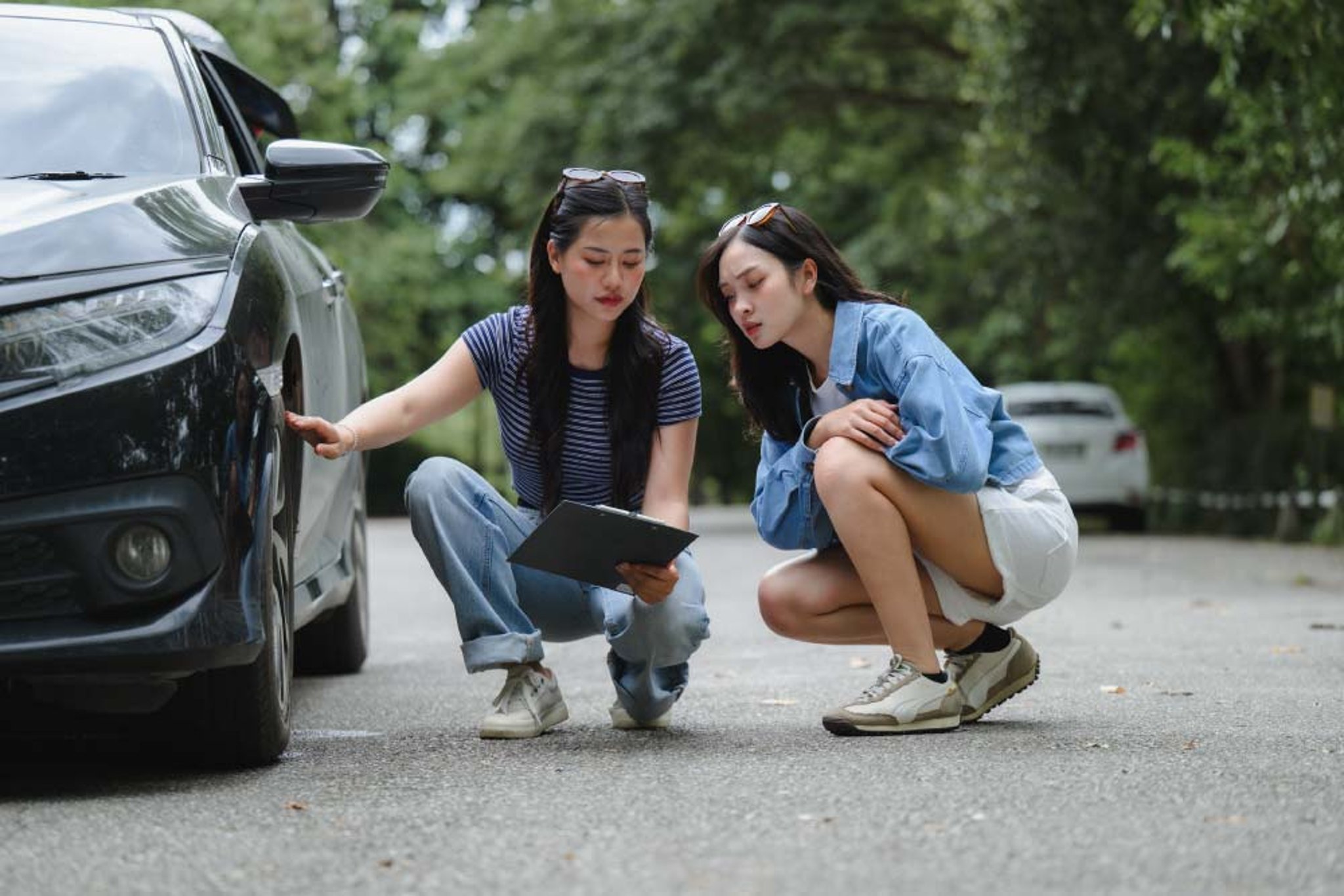 Two sisters reviewing damage on the side of their car