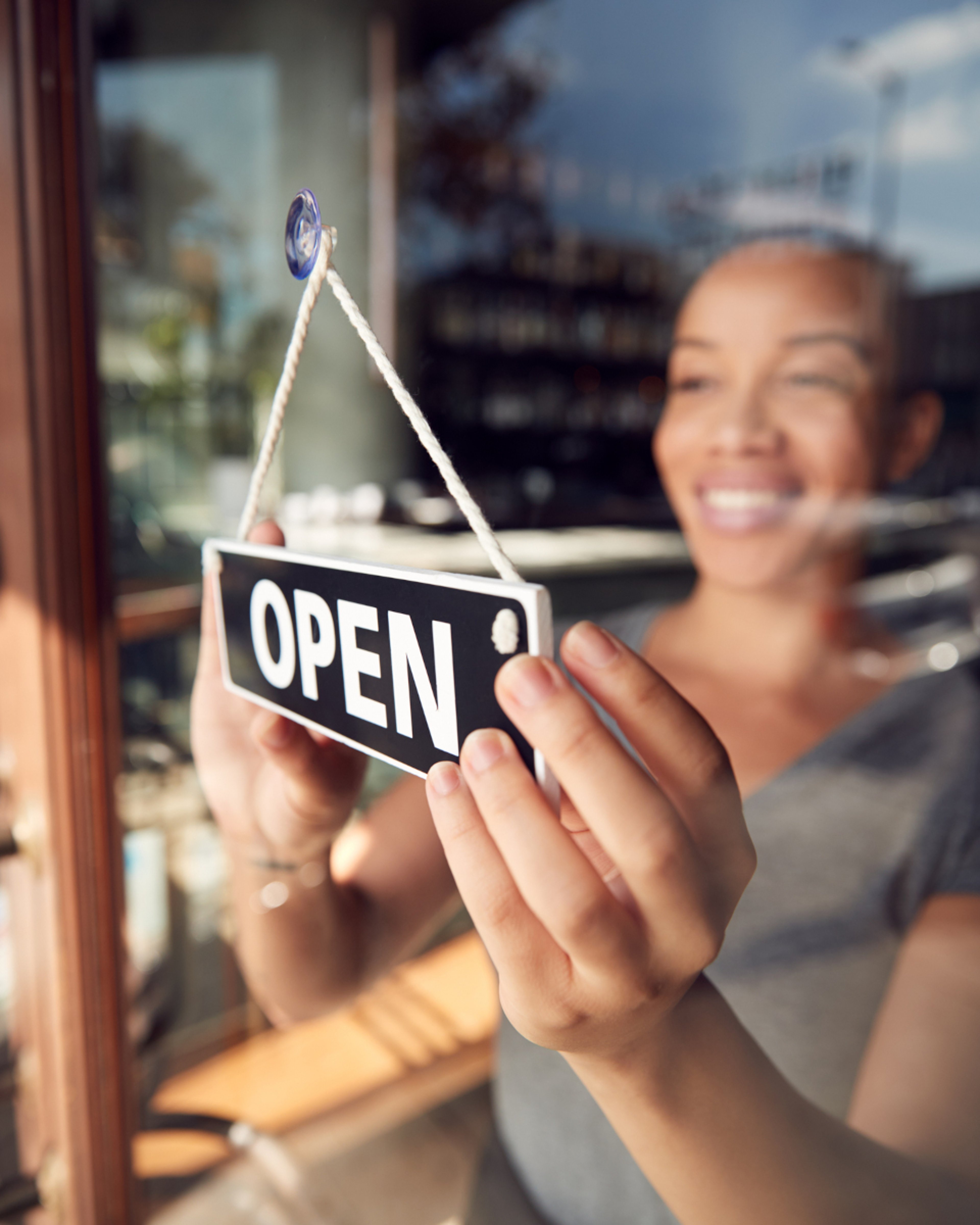 Woman business owner turning over the open sign in her store window