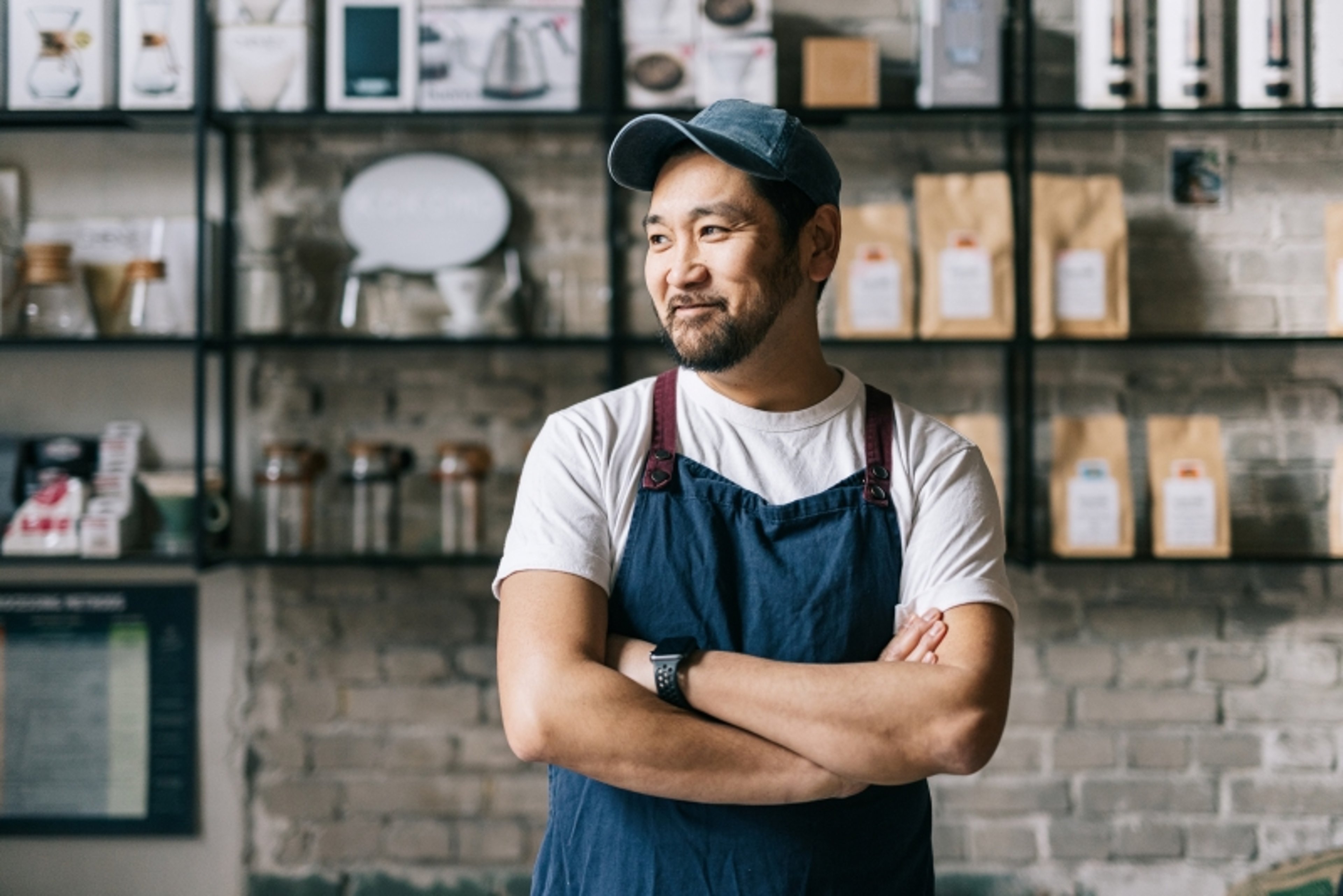 Man with apron smiling in front of shelves