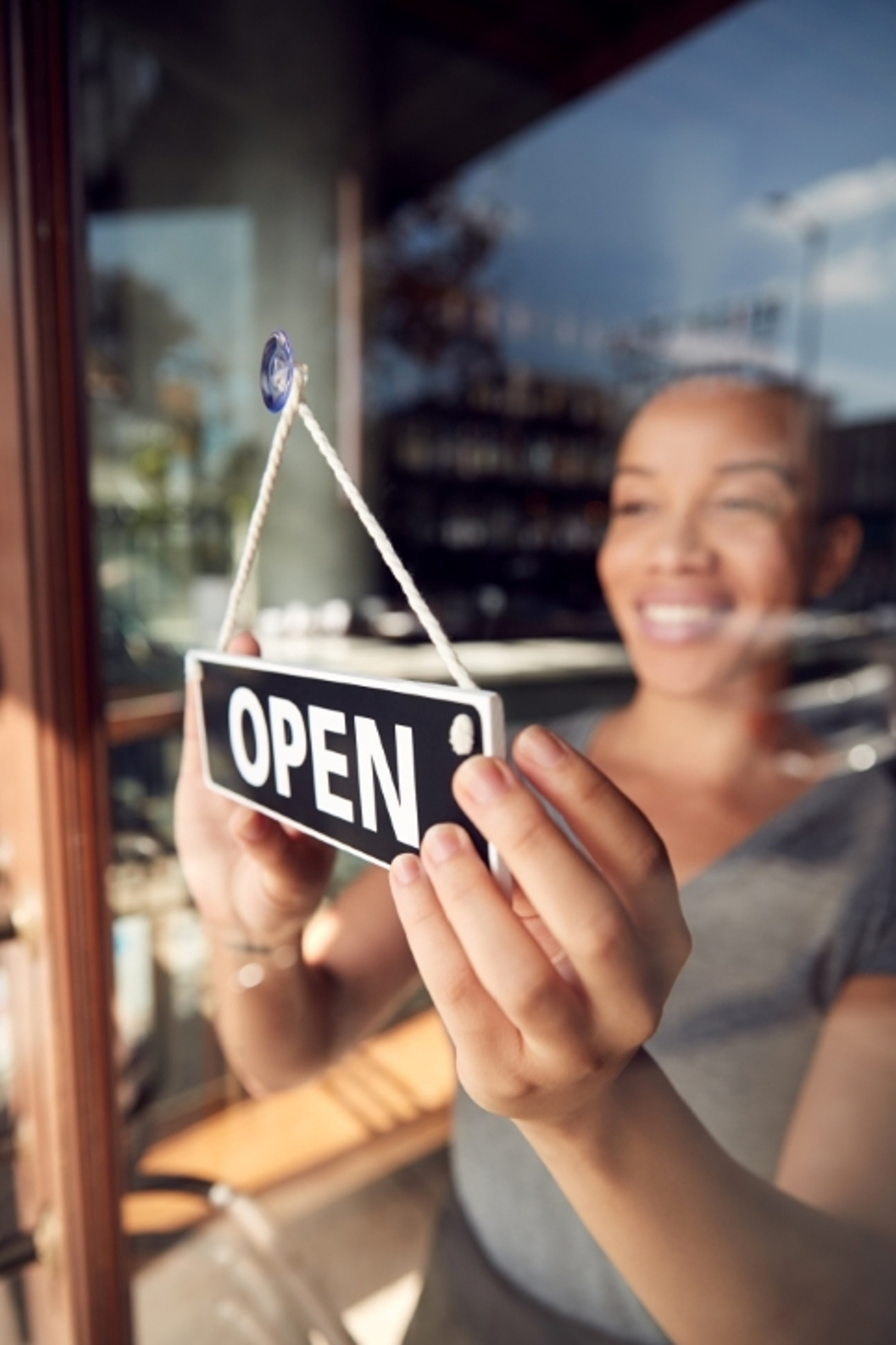 Woman hanging open sign in shop