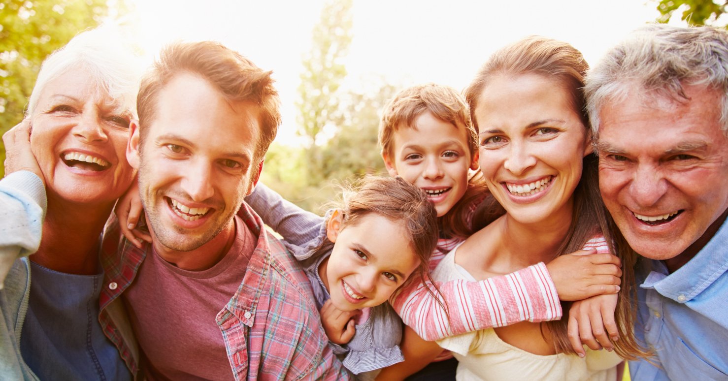 Multigenerational family smiling and hugging on sunny day in a park