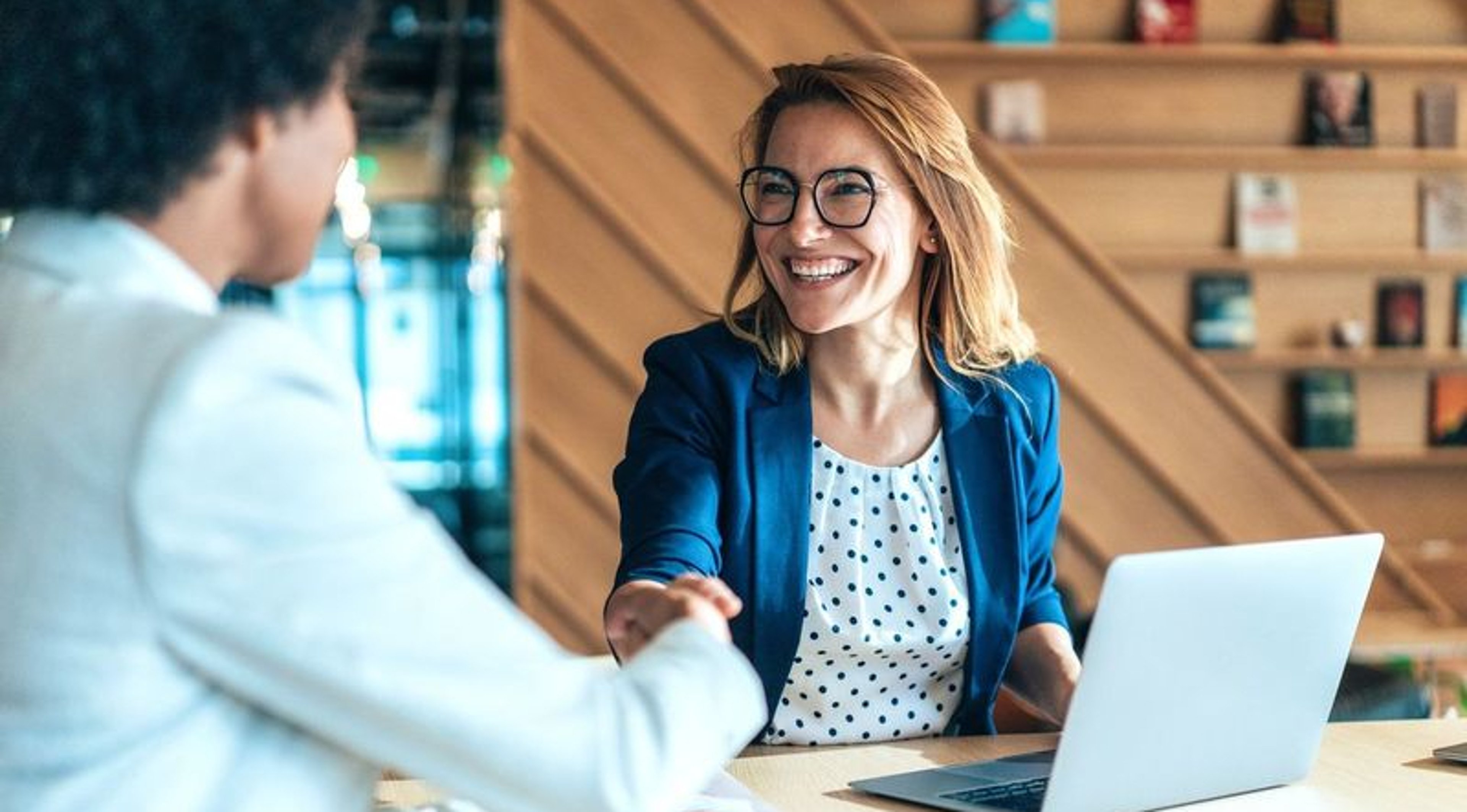 Female agent with laptop shaking hands with client