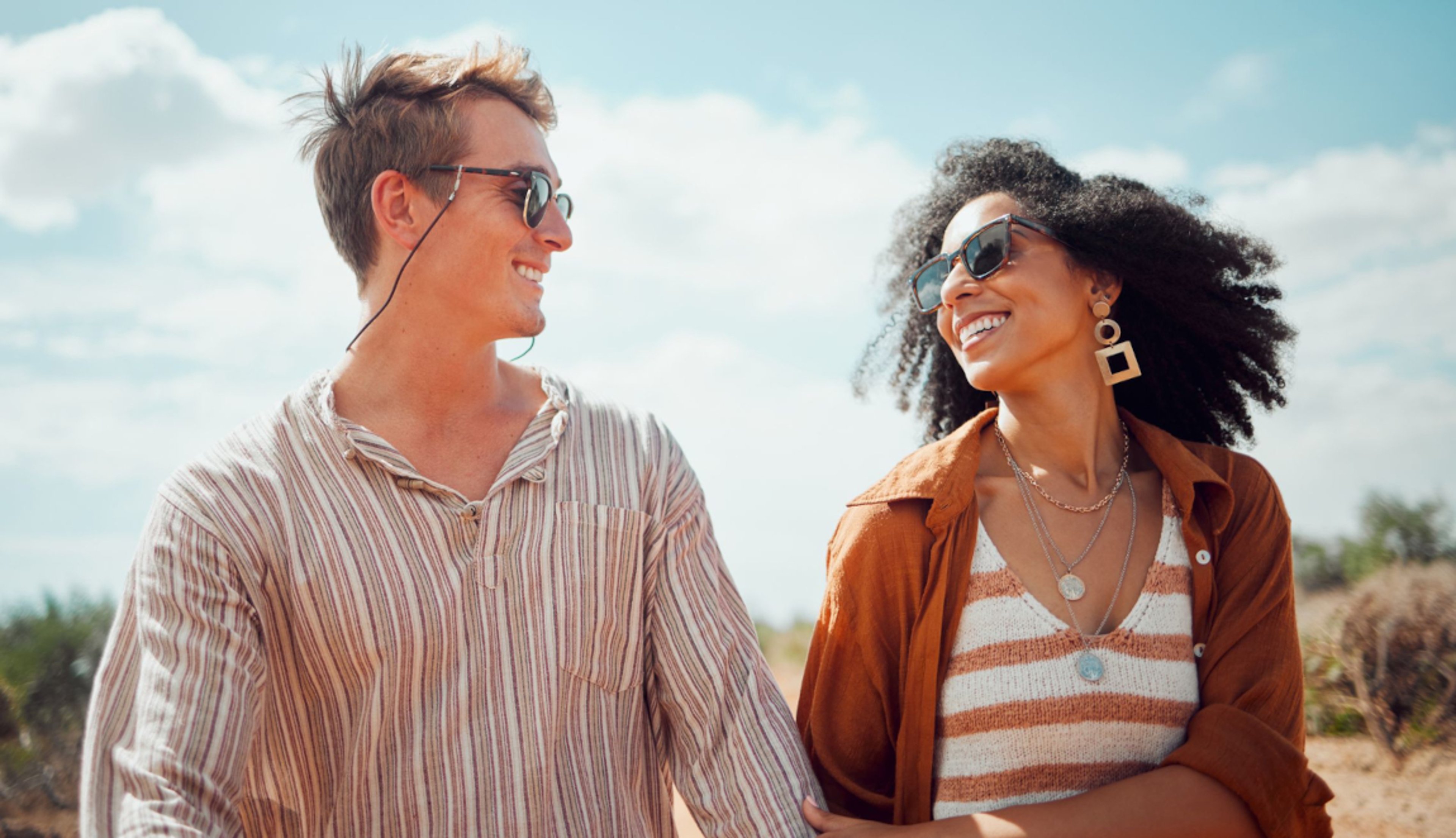 Man and woman couple with sunglasses looking at each other on a sunny beach