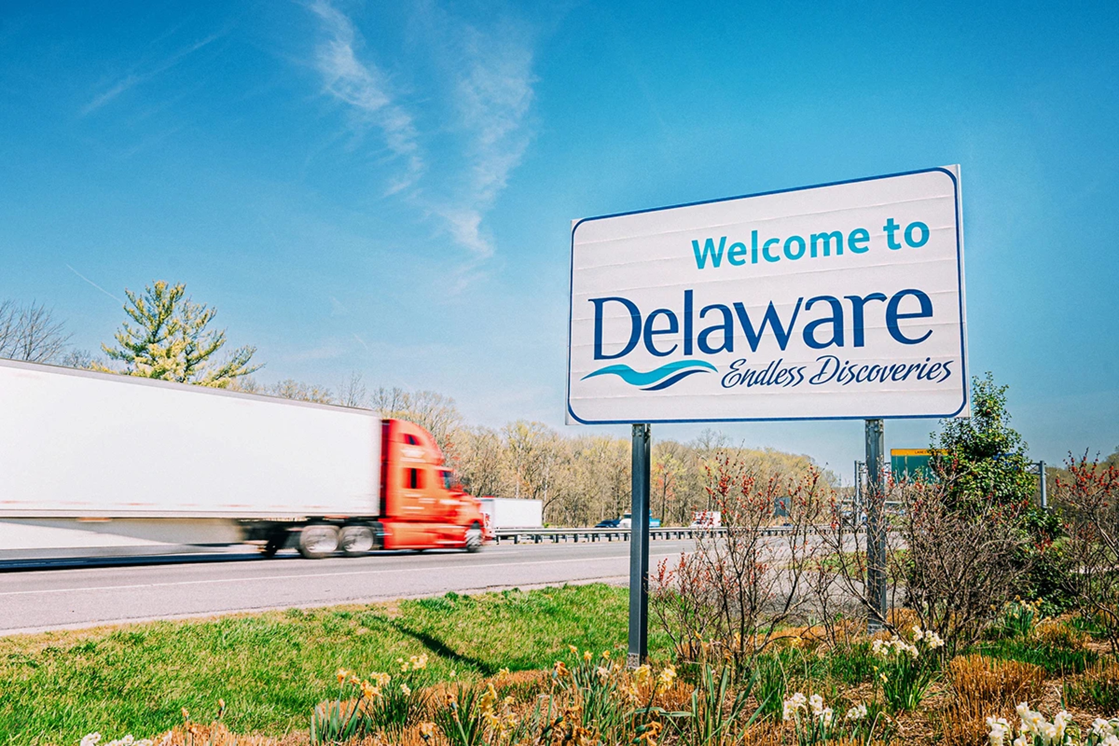 Welcome to Delaware sign at side of highway with truck driving past