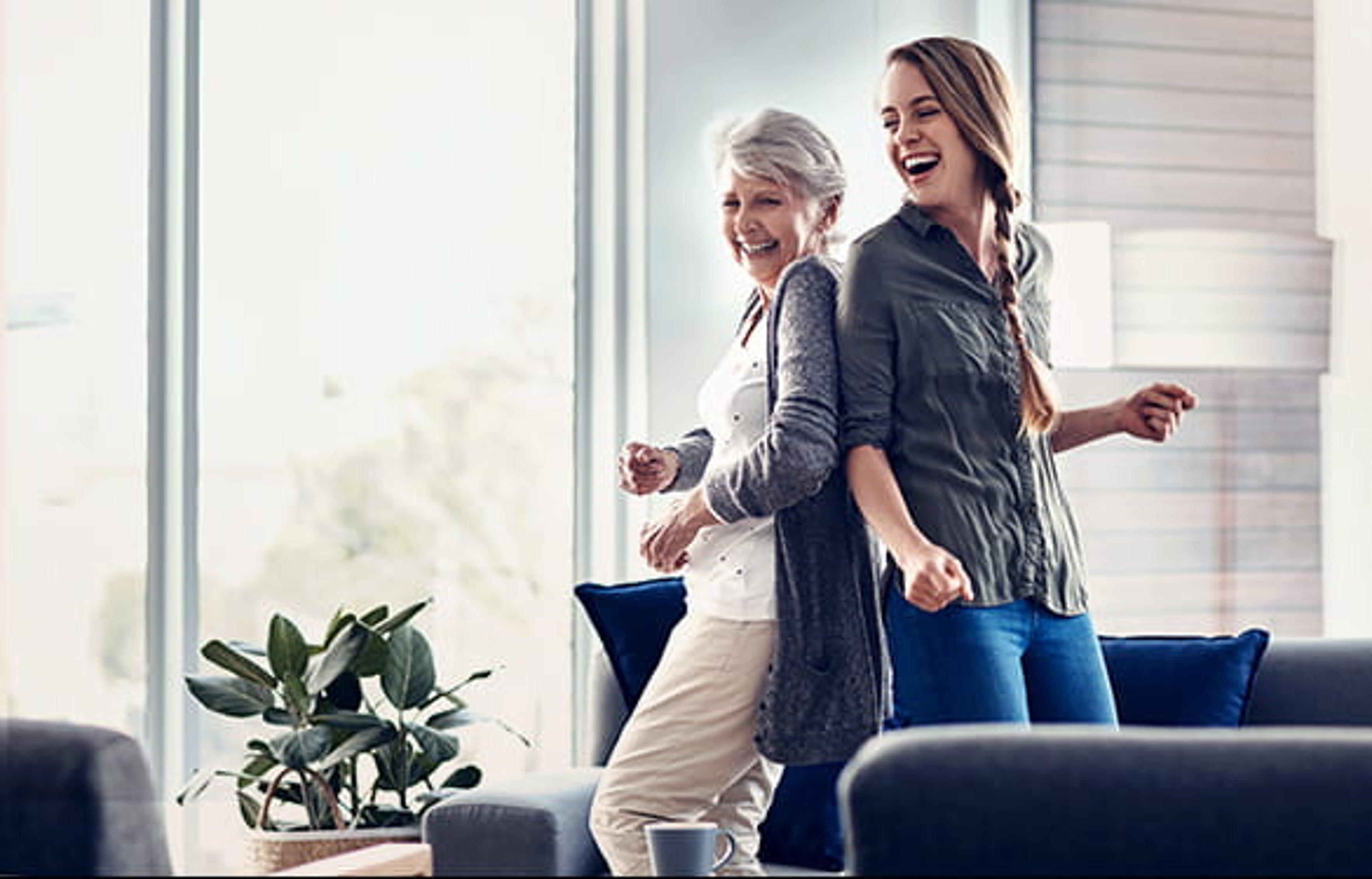 Happy mother and adult daughter dancing in living room