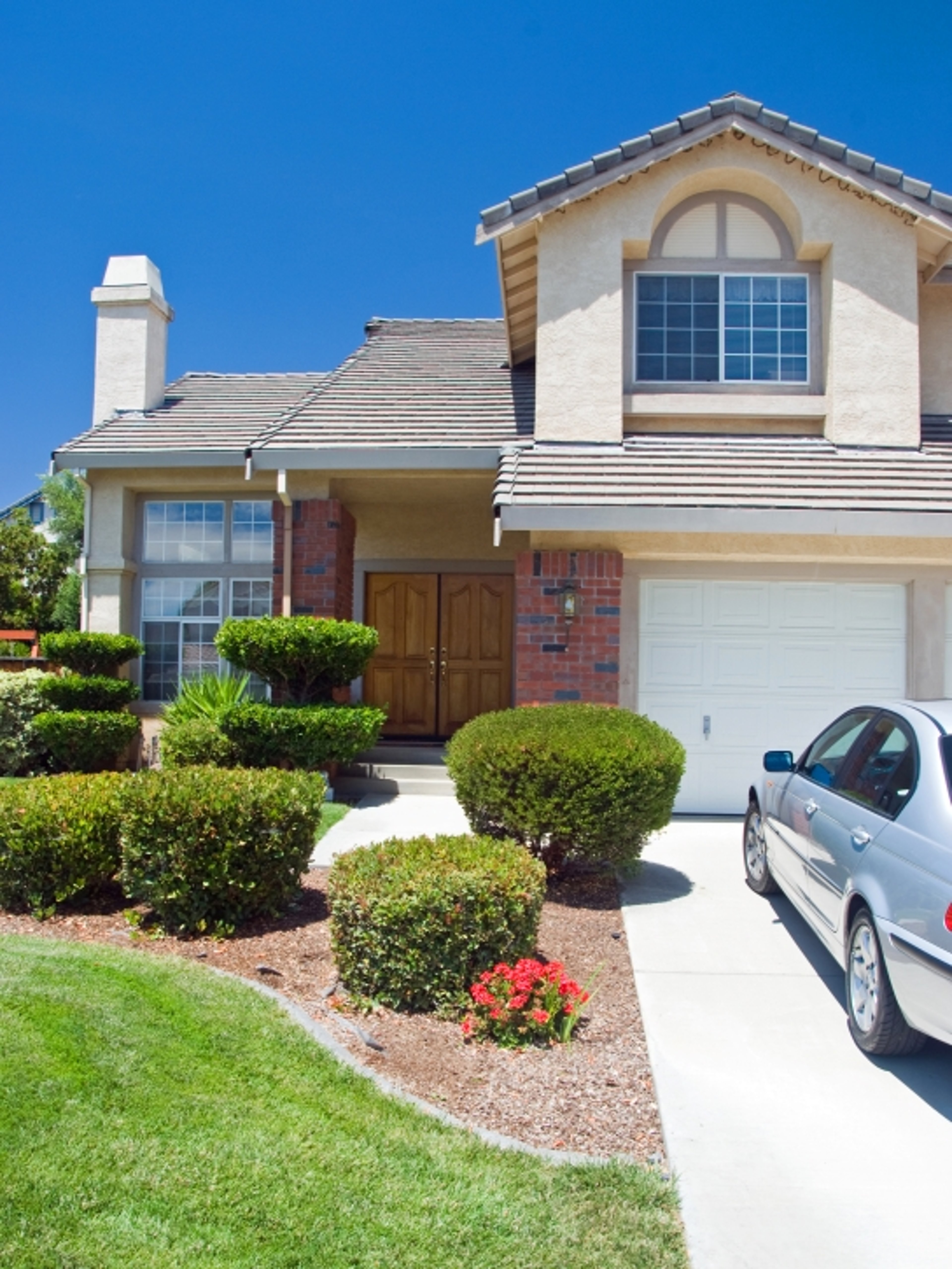 Silver car in driveway with bushes