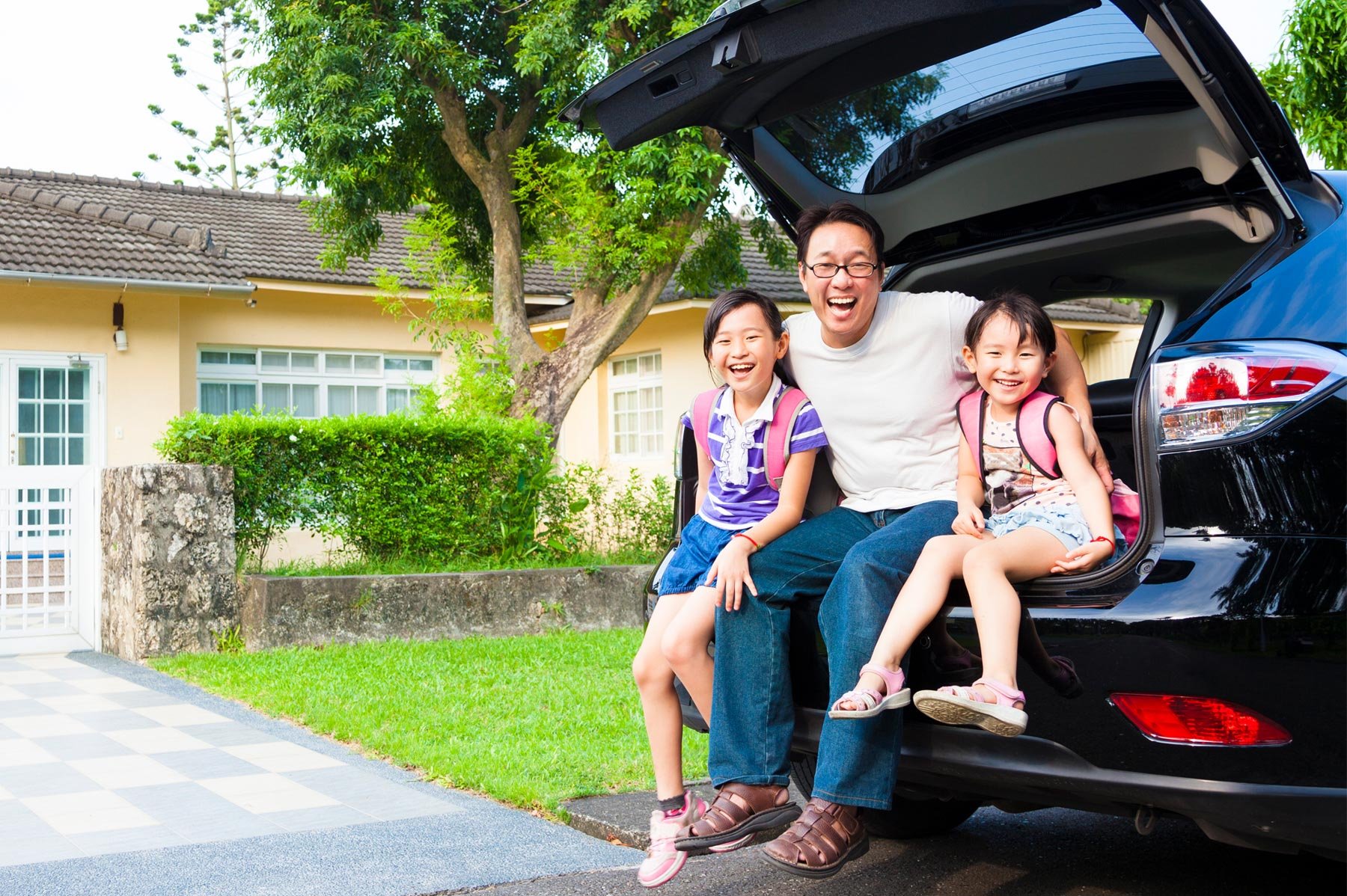 Family smiling sitting in car trunk