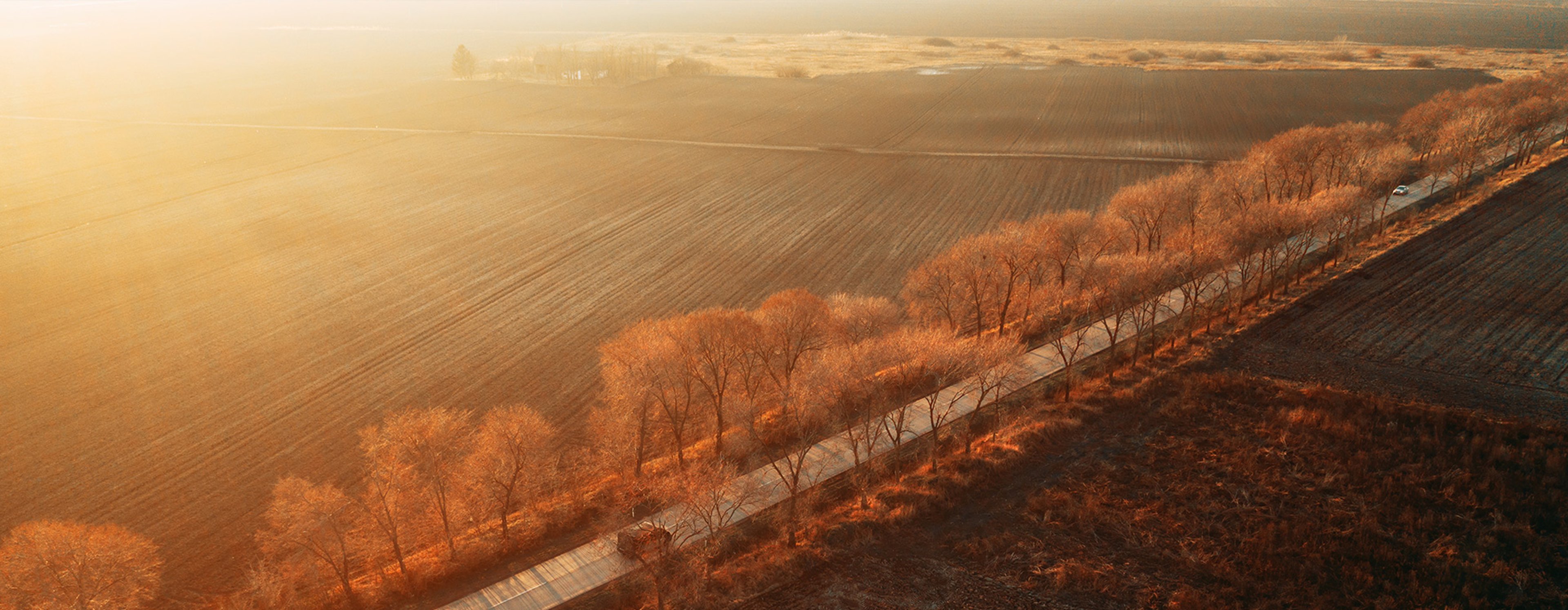 Sunset over an Autumn landscape with cars driving over the road. 