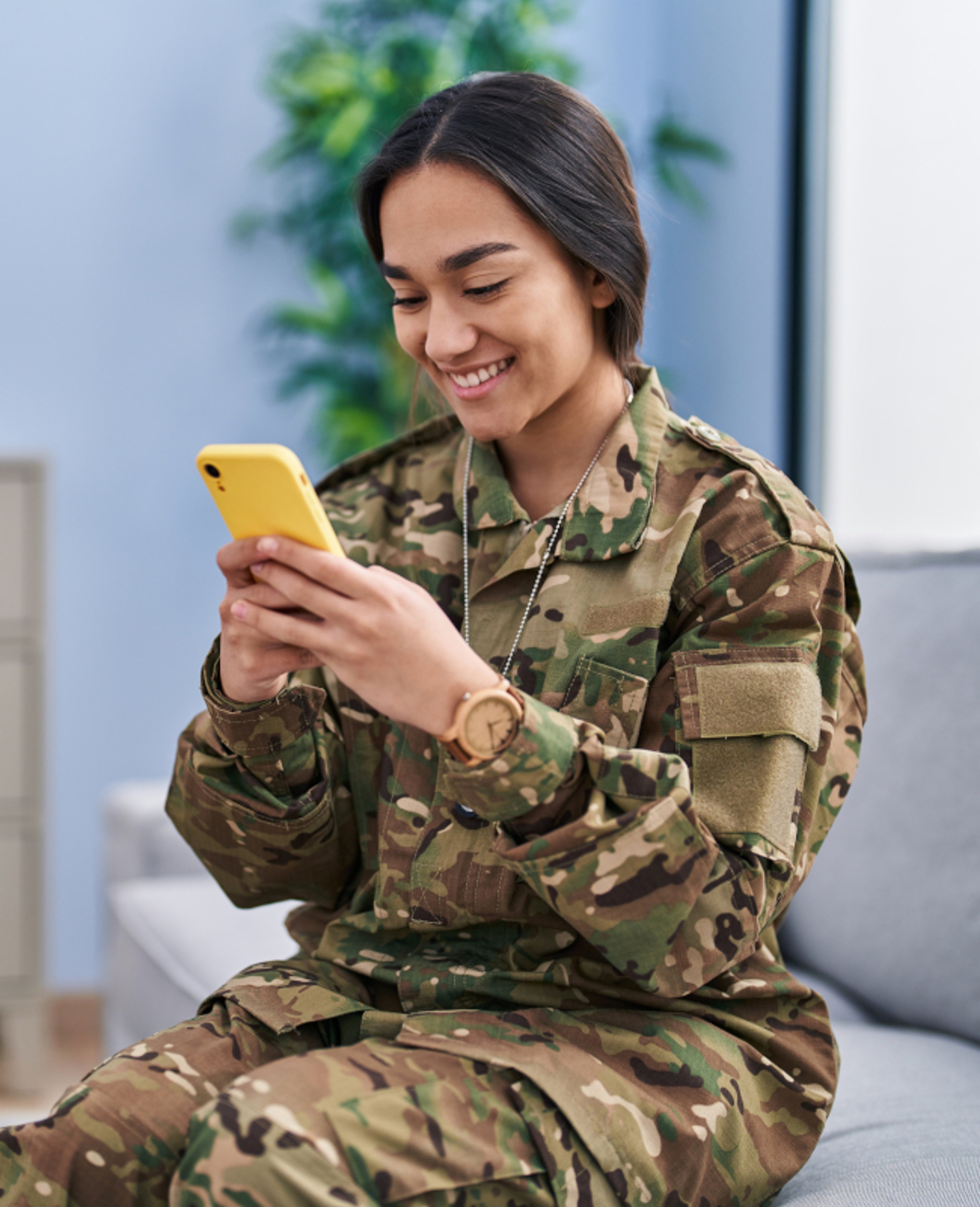 Young woman army soldier using smartphone at home 