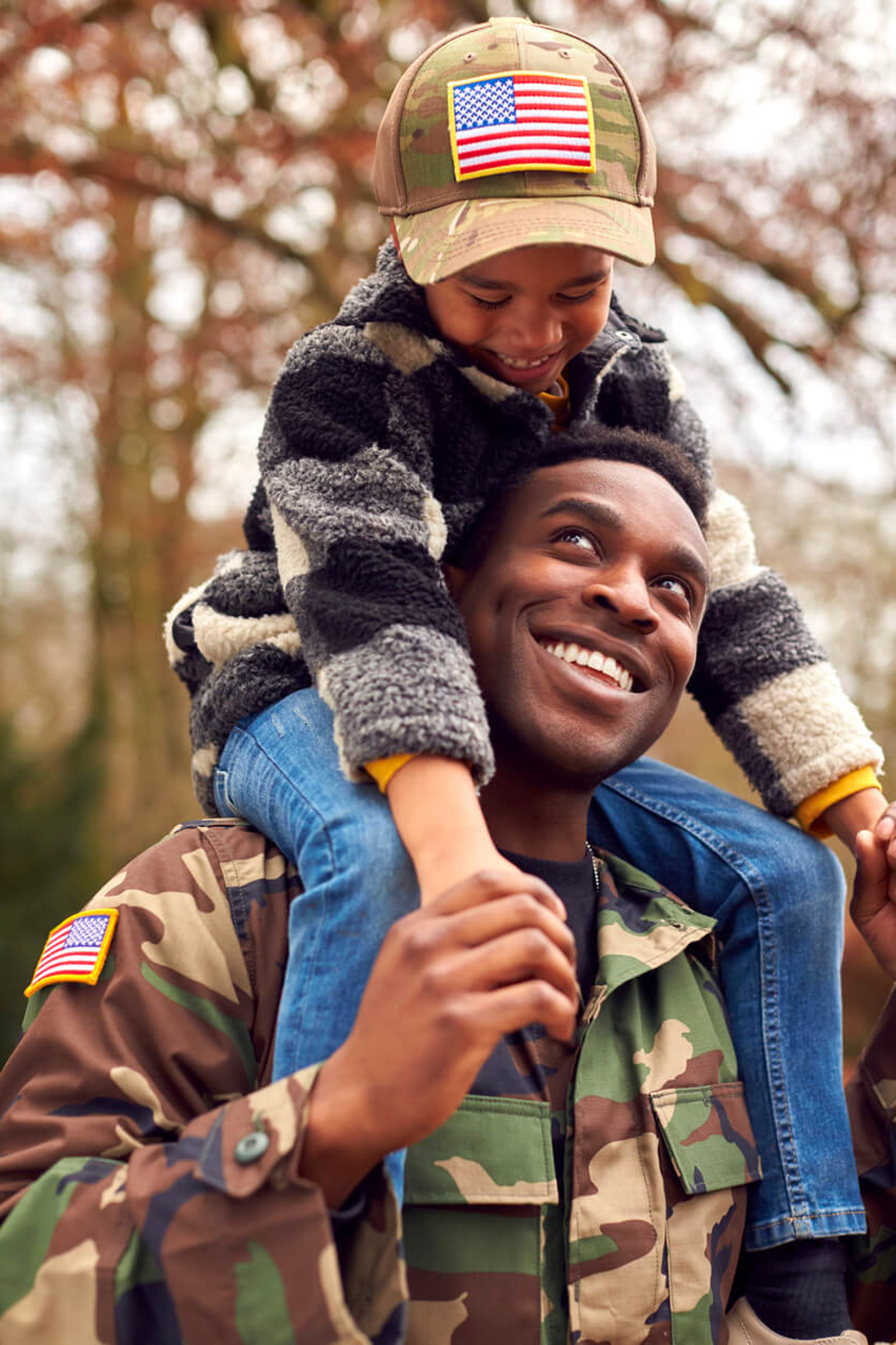 Smiling serviceman carrying his child on his shoulders