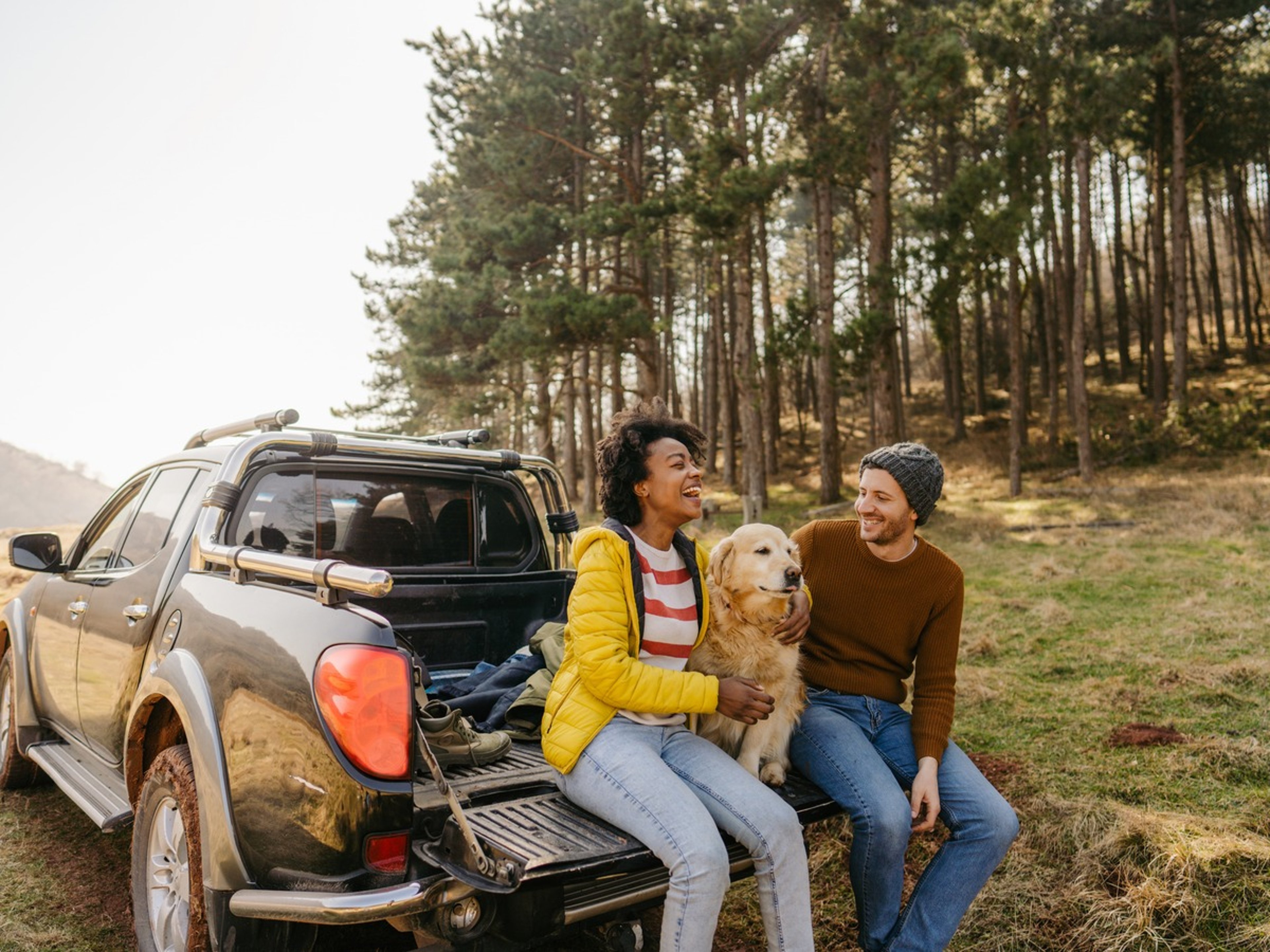 Couple relaxing with their dog beside a pickup truck