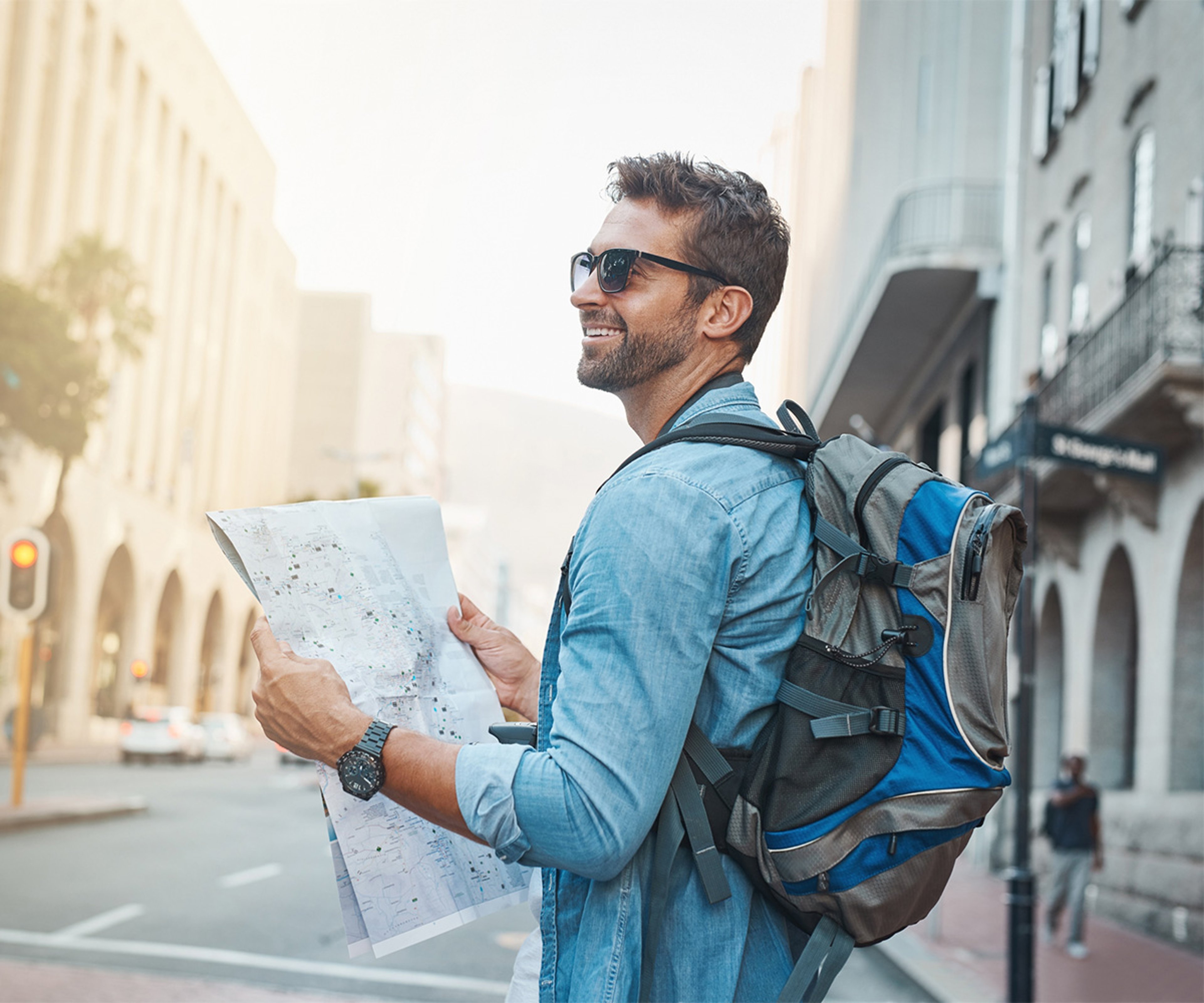 Man with backpack on city street holding travel map on vacation