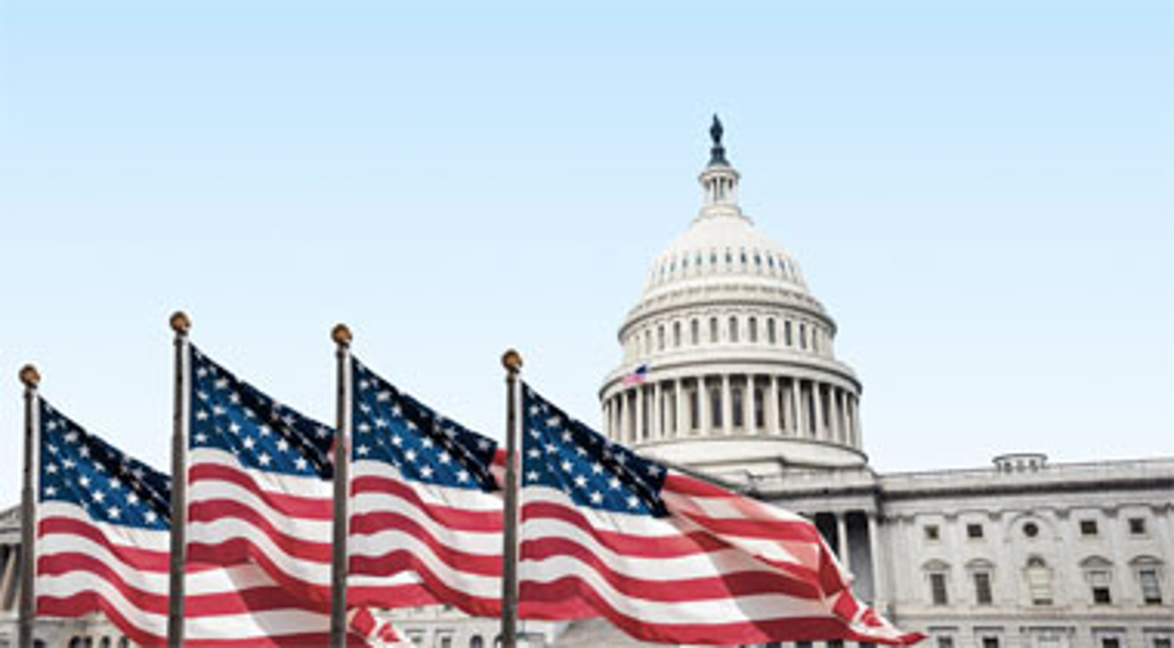 U.S. National flag waving in the wind with city hall in the back