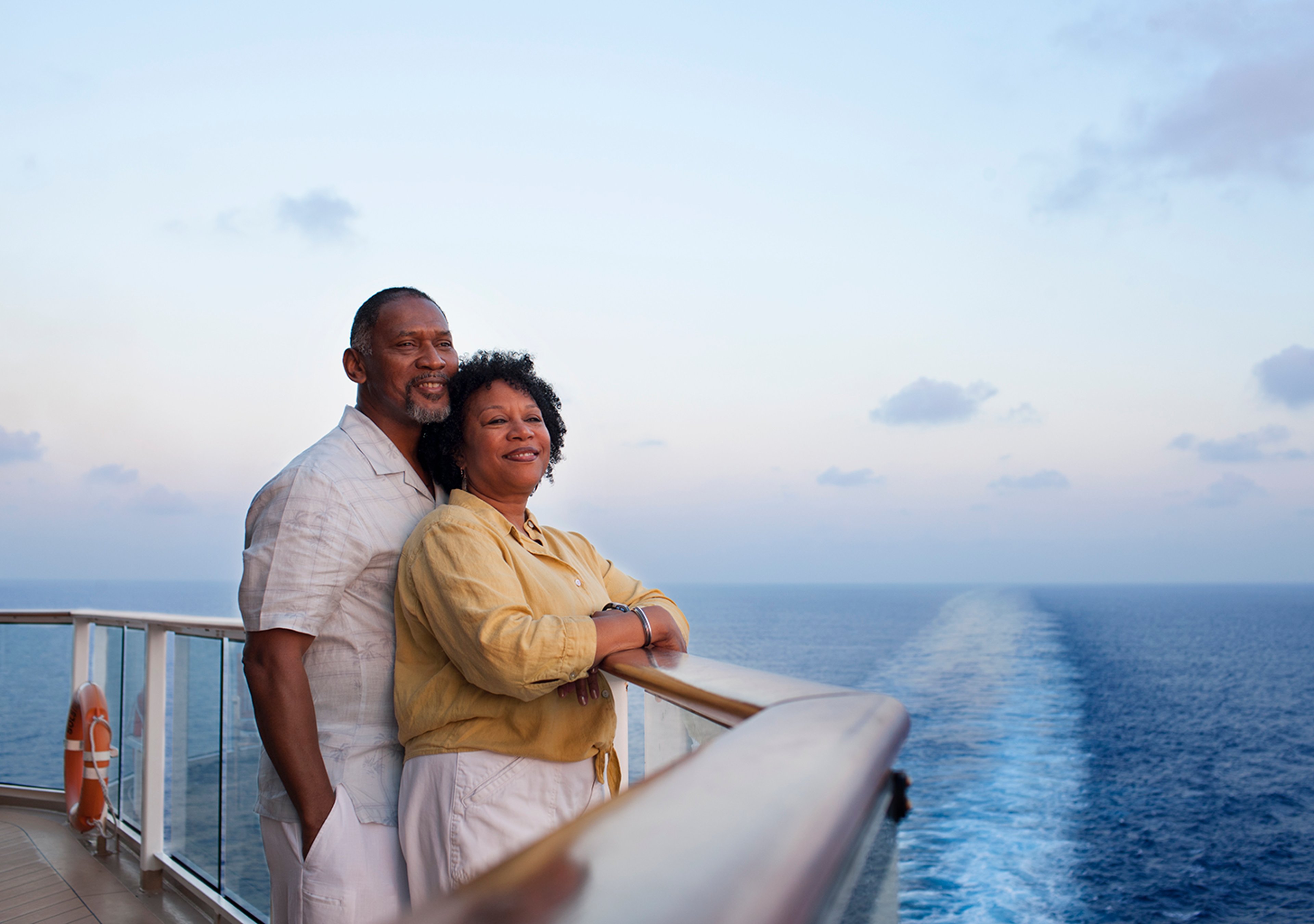 Happy older couple looking out over the sea from the deck of their cruise ship