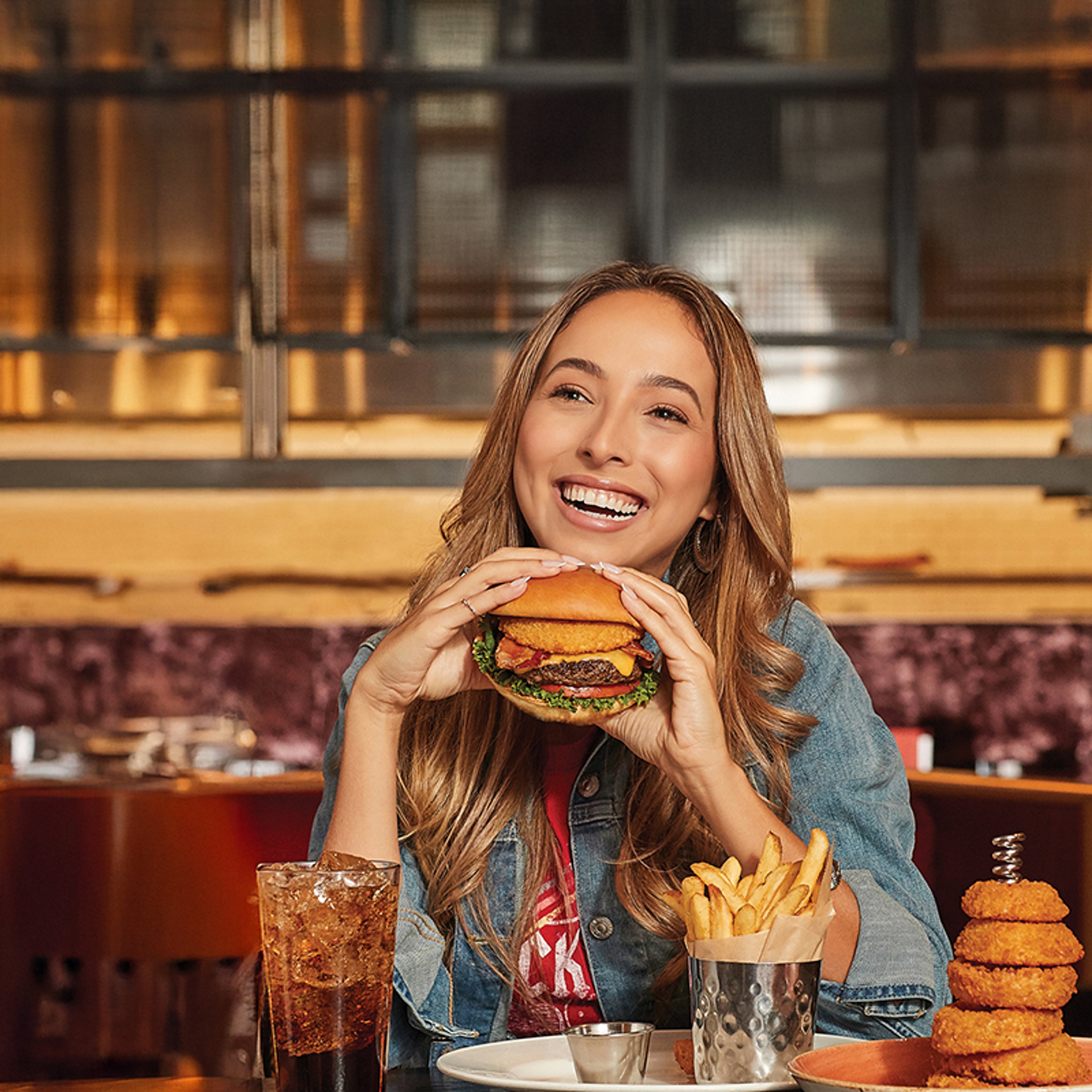 Smiling woman holding a cheeseburger in a restaurant