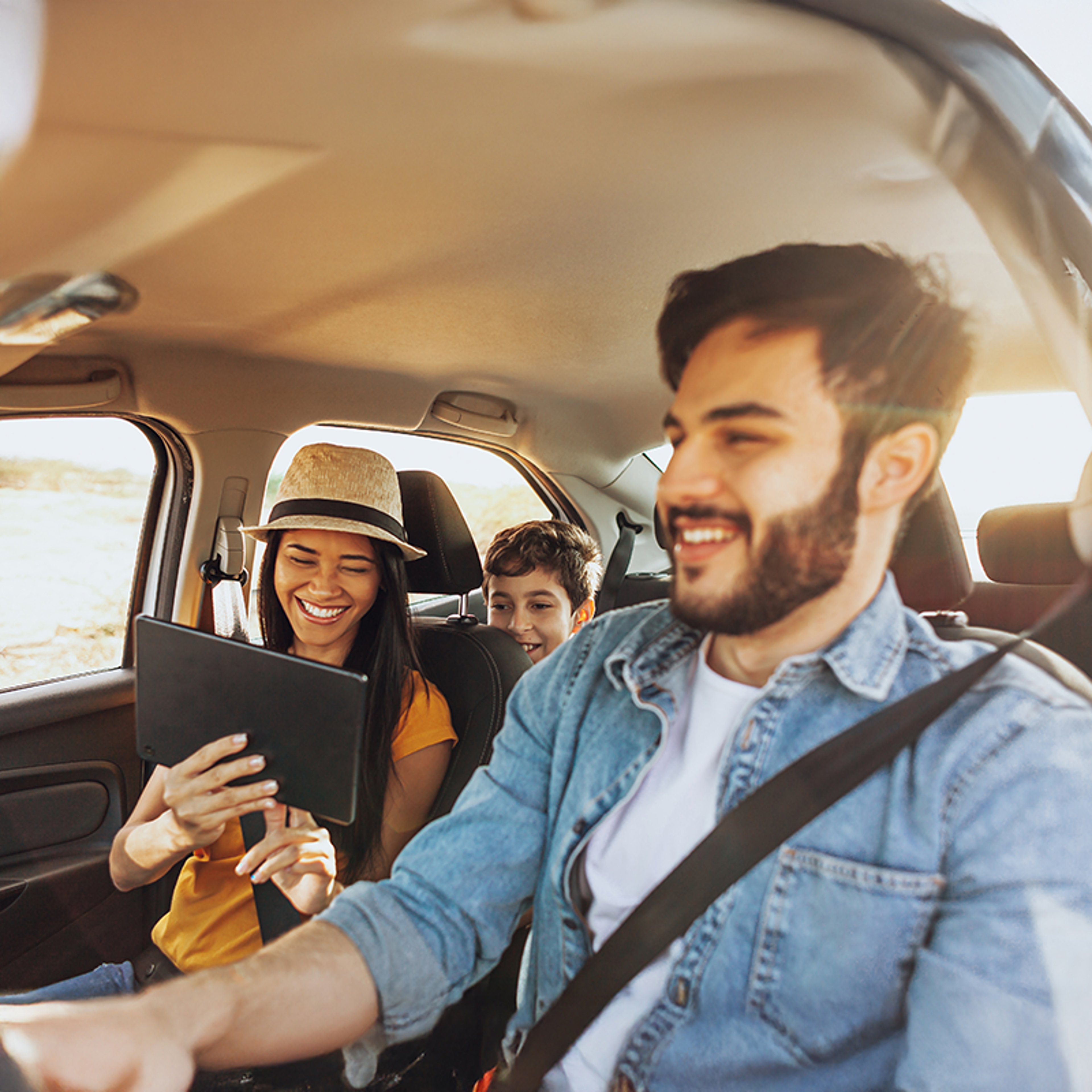 Family of three driving in car with smiling mother looking back at kids in back seat