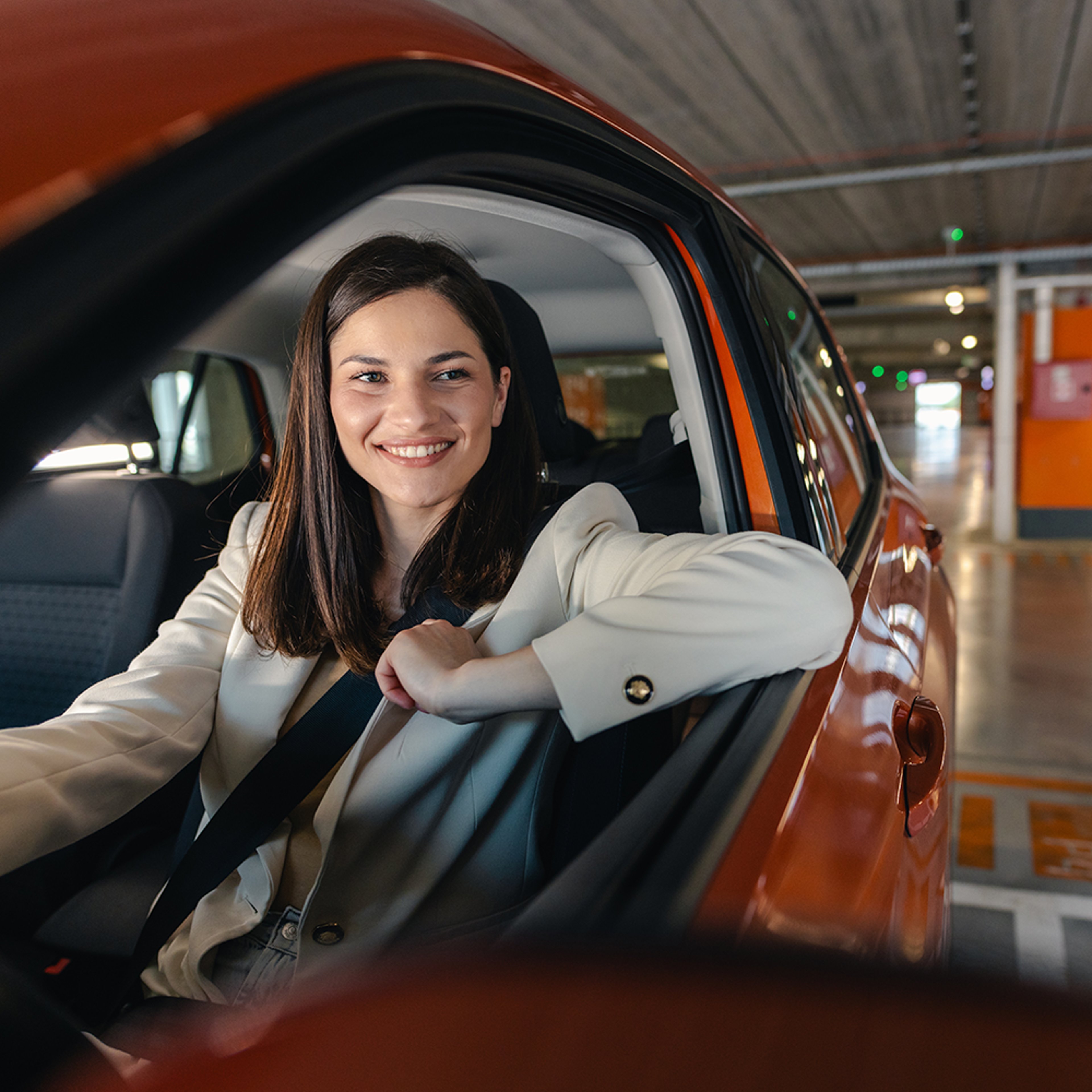 Woman smiling while driving car out of parking garage