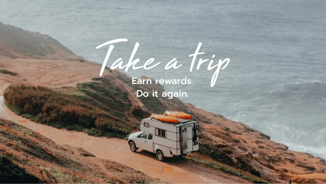 A scenic coastal view with a white camper truck parked on a dirt road near the ocean. The text overlay reads "Take a trip. Earn rewards. Do it again." promoting the concept of earning travel rewards through trips.
