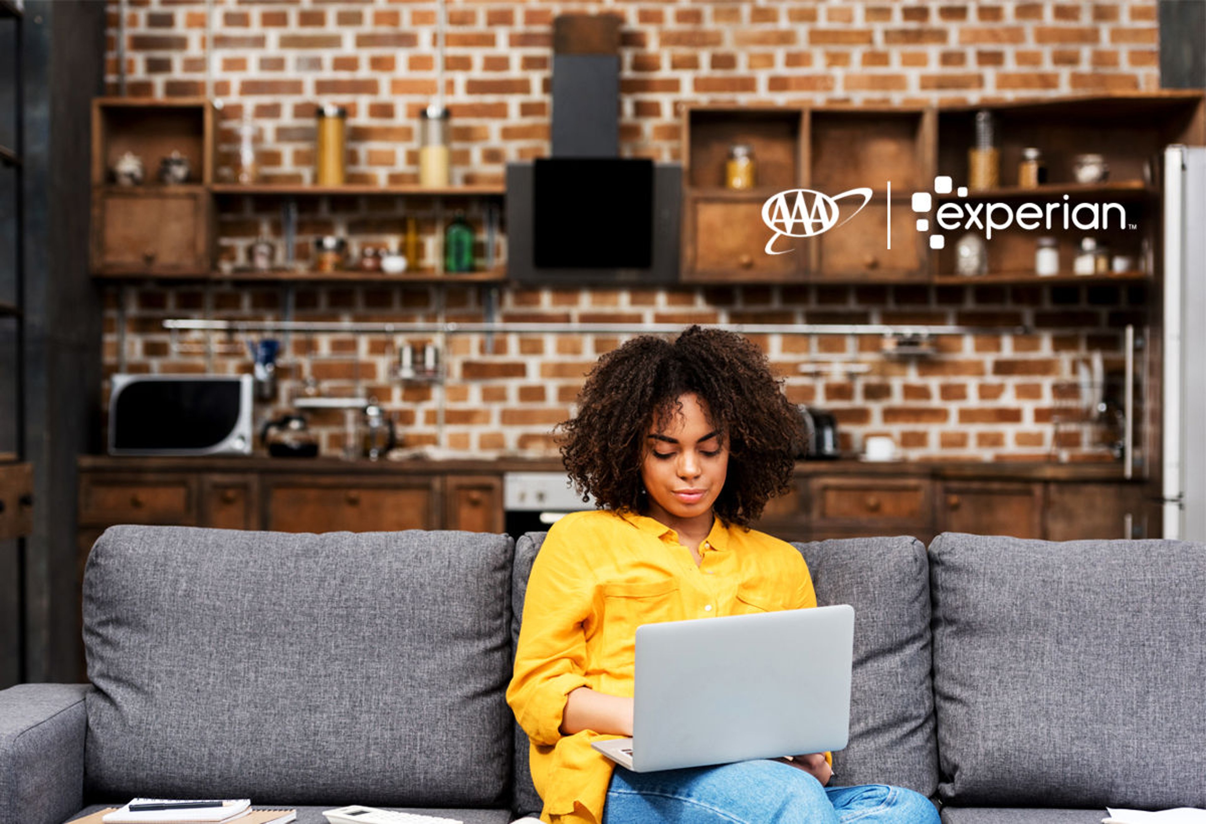 Woman sitting on gray sofa searching laptop for credit protection information