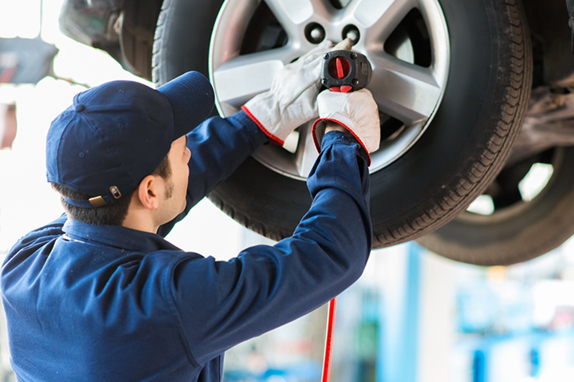 Car mechanic bolting wheels on to car