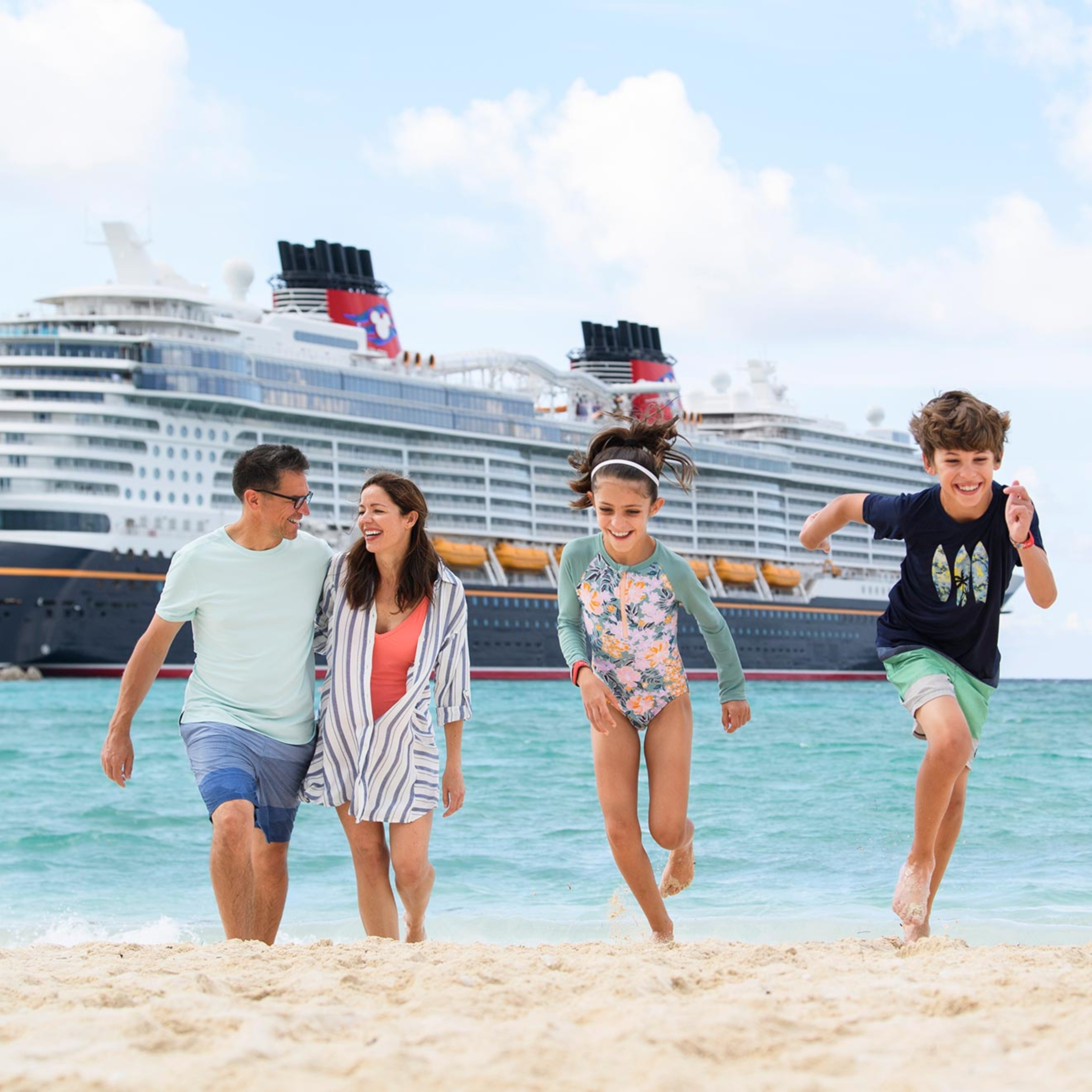 Family on beach in front of a Disney Cruise ship