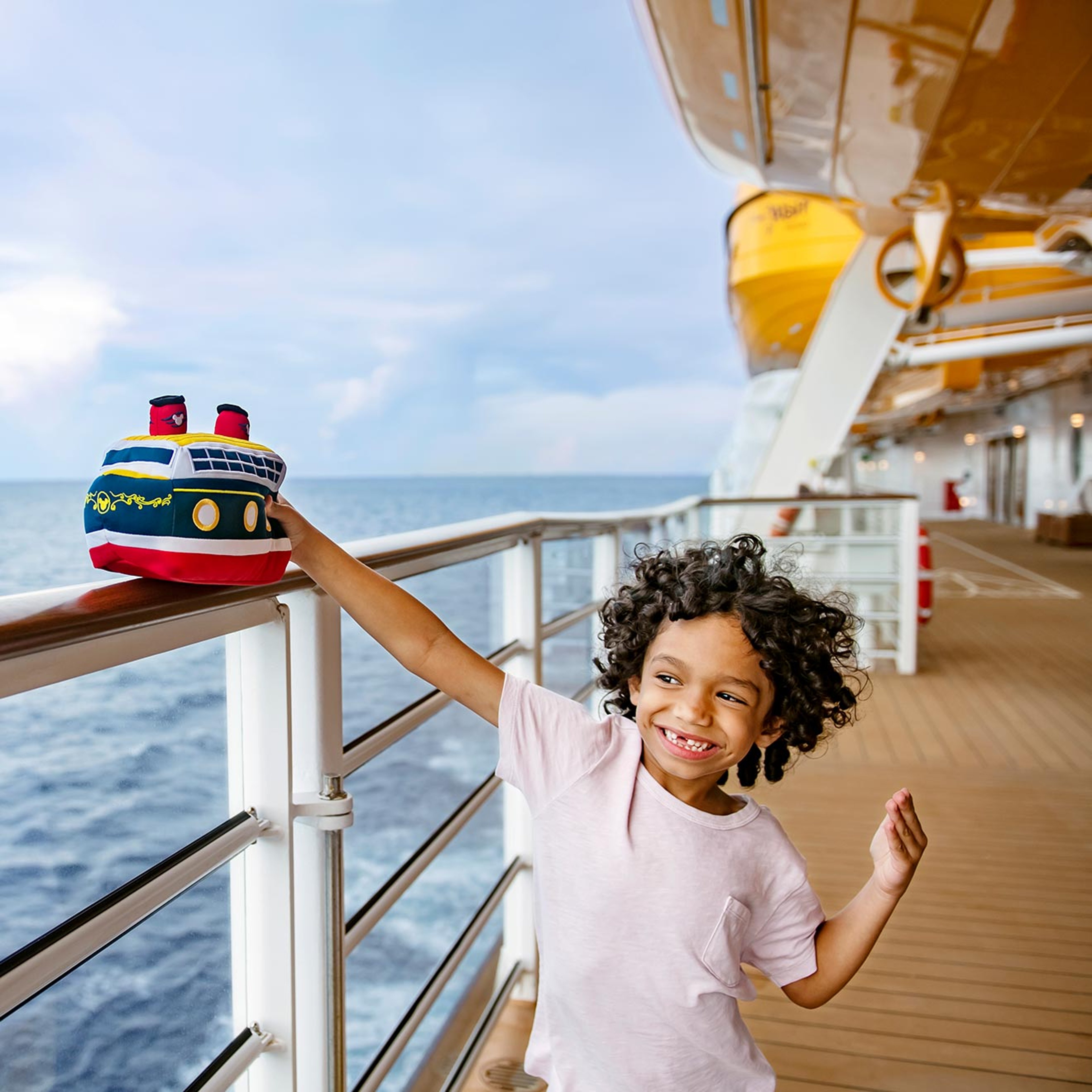 Child with stuffed Disney ship replica on the deck of a real Disney ship
