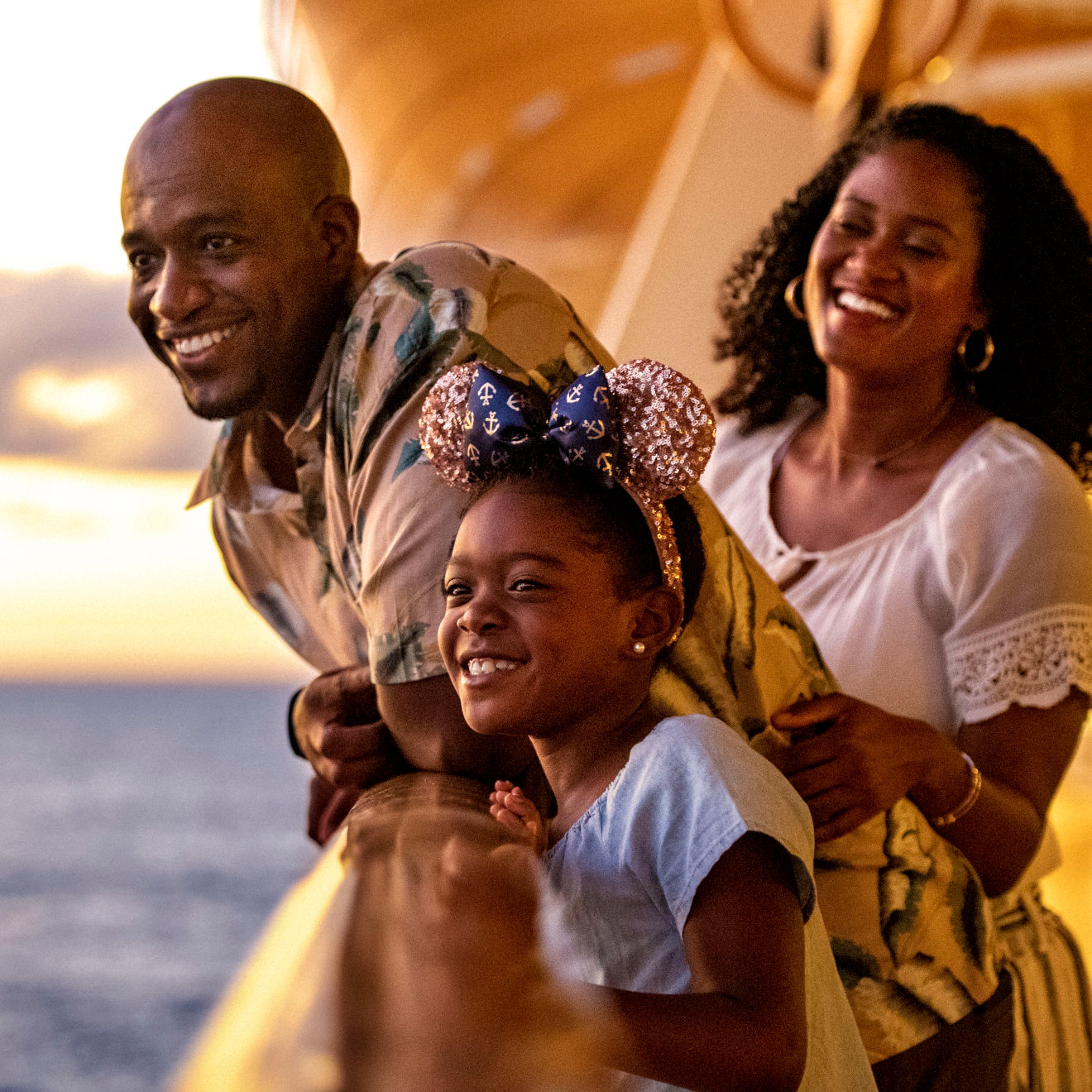 Smiling family on deck of Disney Cruise ship at sunset