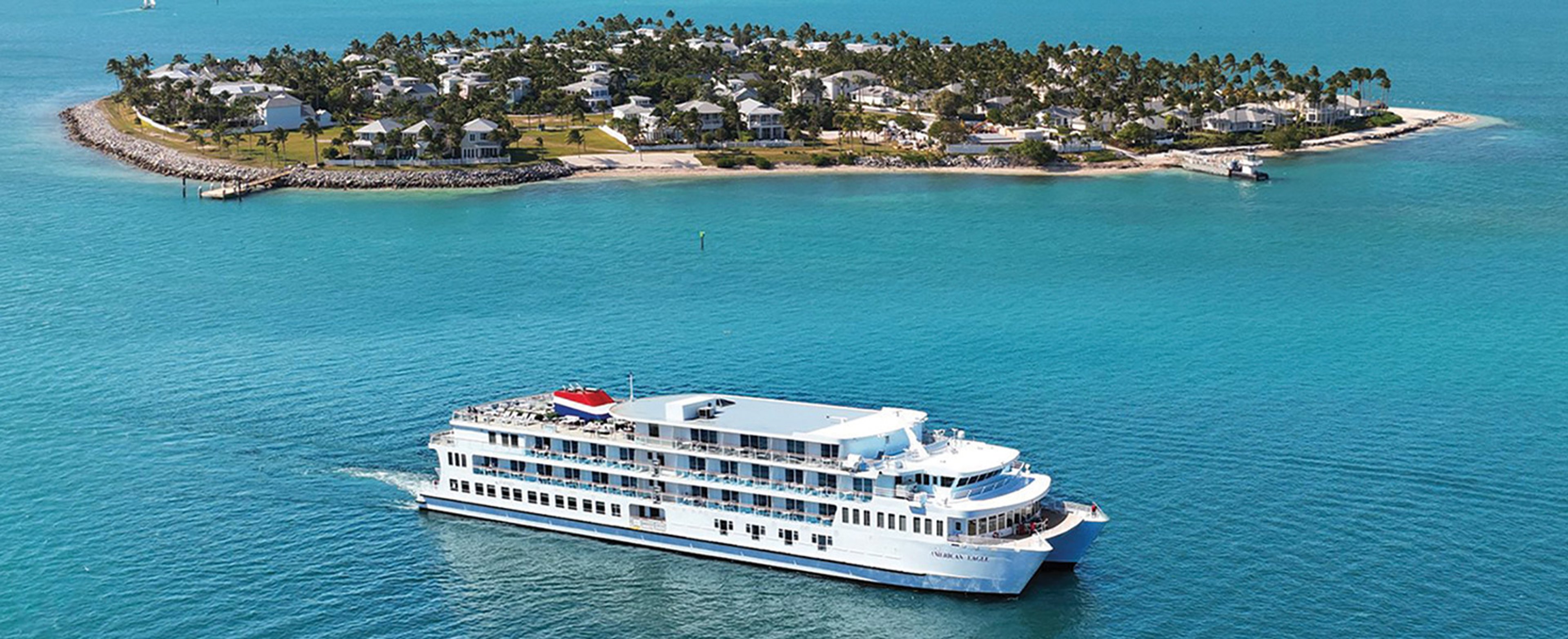 An American Cruise Lines coastal catamaran sails near a tropical island during an itinerary like the Florida Coast or Keys cruise