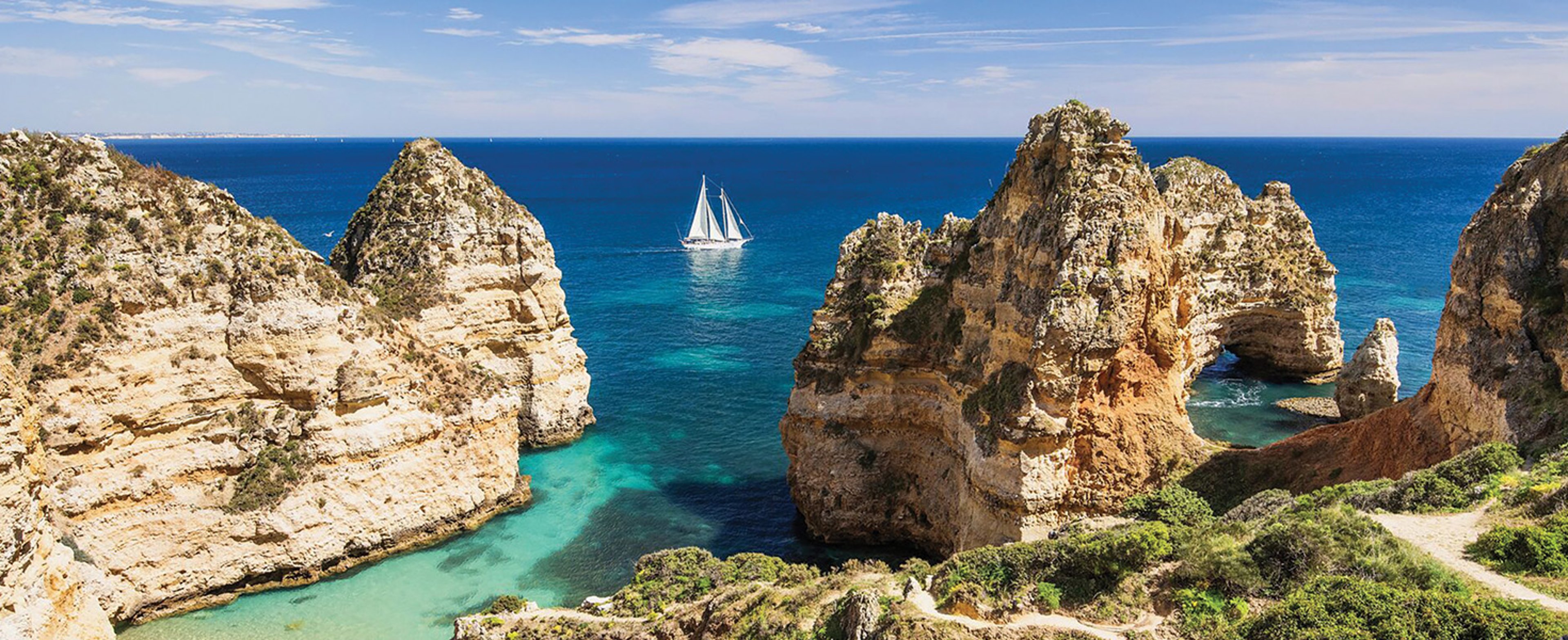 This is Marinha Beach, located in the Algarve region of Portugal, featuring clear turquoise waters and golden limestone cliffs